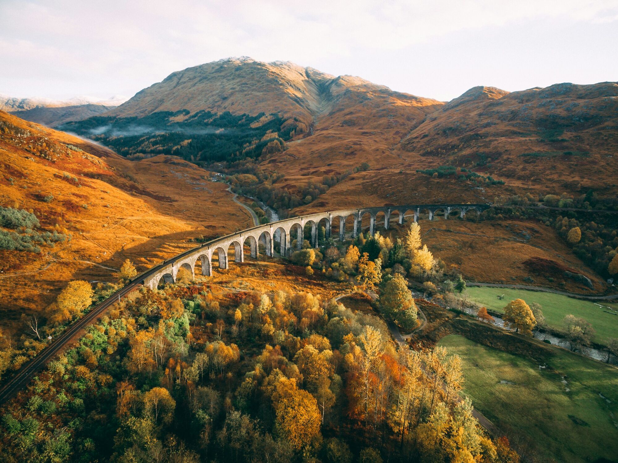 Curving railway viaduct amid autumn trees and mountains