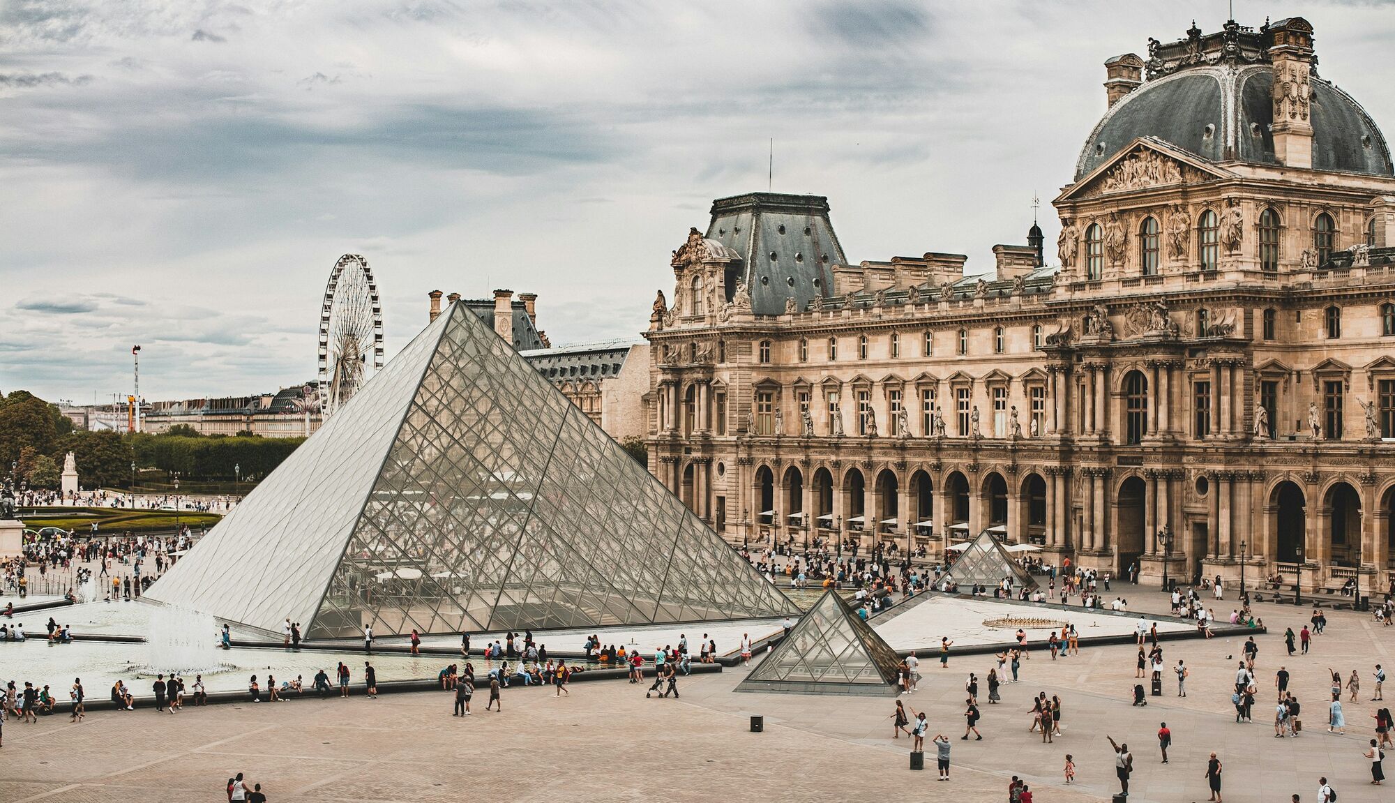 Visitors beside Louvre Museum glass pyramid