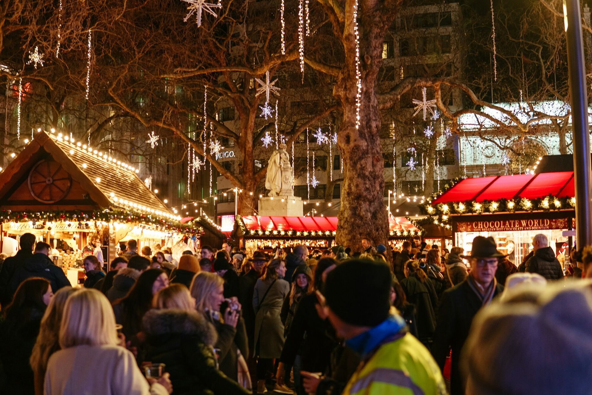 Crowded Christmas market with illuminated wooden stalls at night