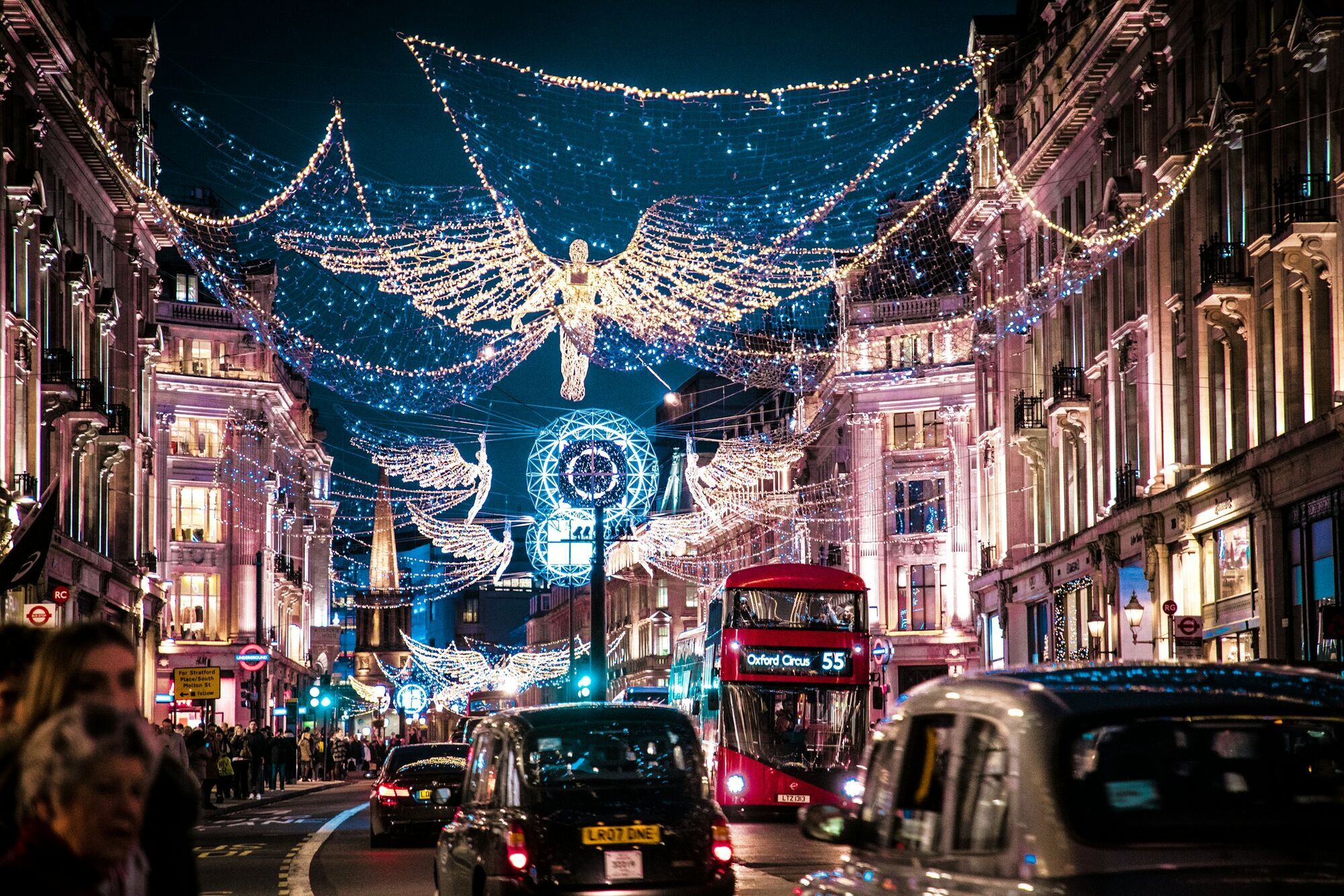Passengers photographing illuminated Christmas angels from an open-top bus in London
