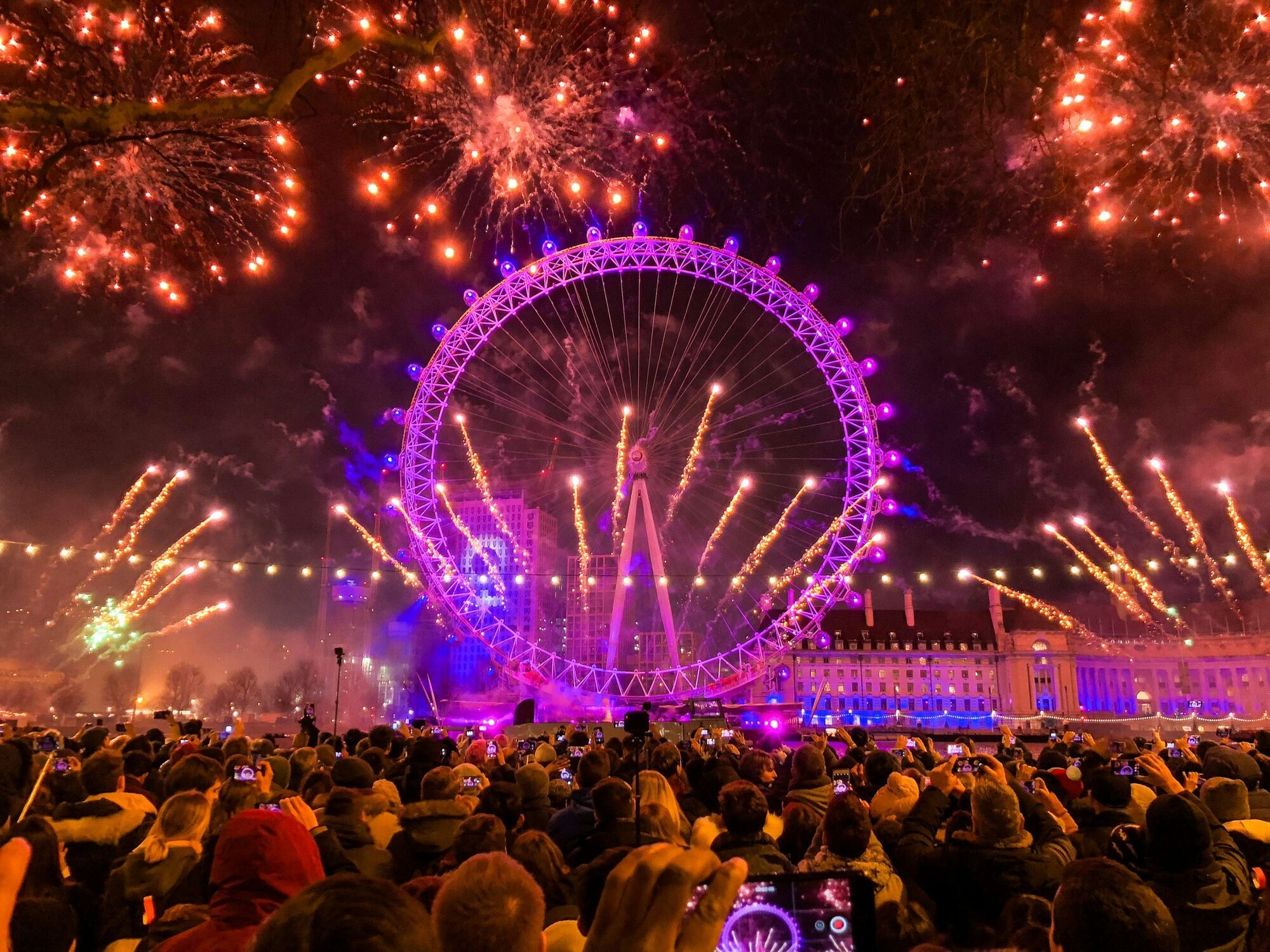Crowds watching fireworks around the illuminated London Eye