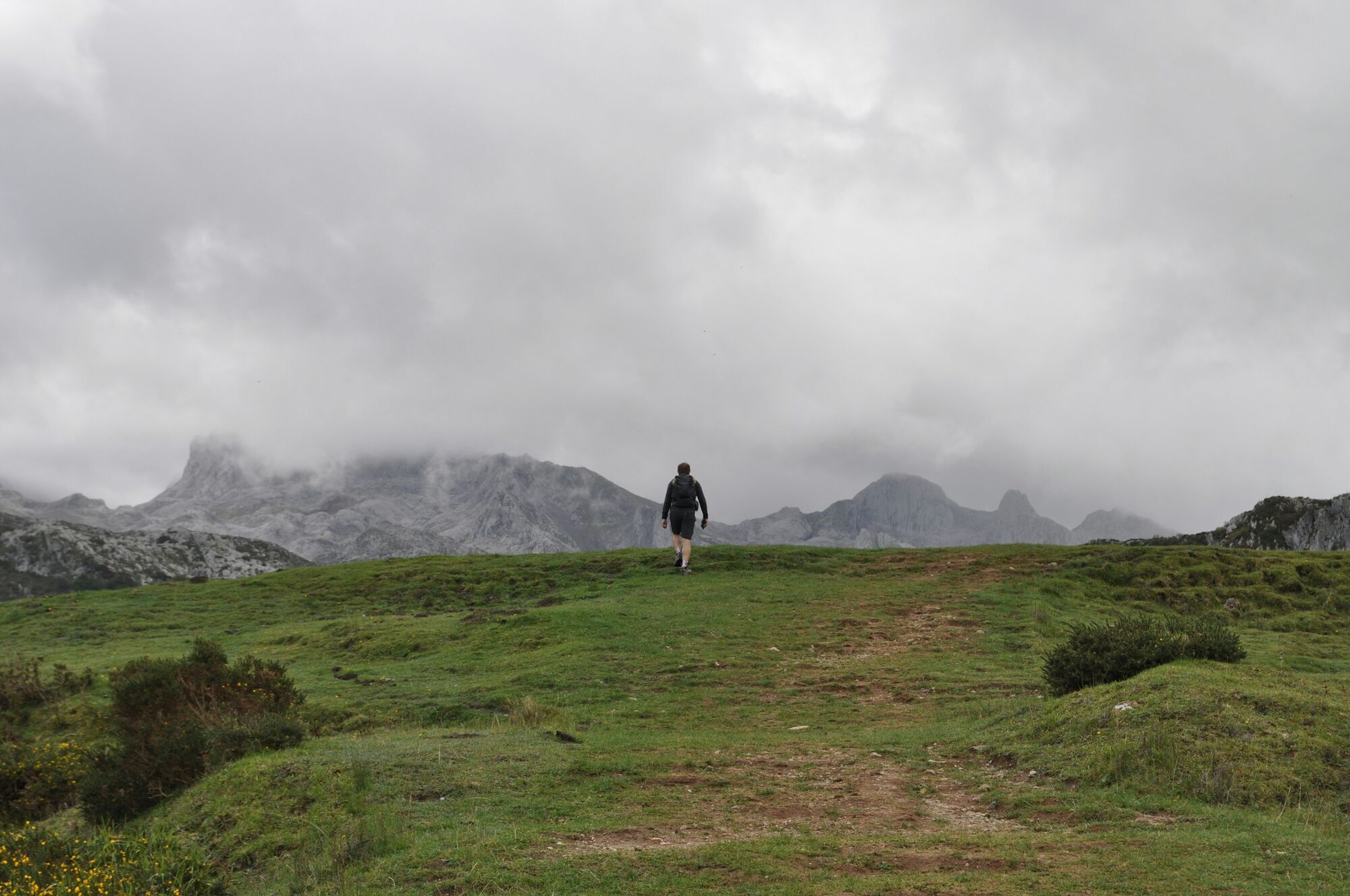Hiker walking towards mist-covered mountains in northern Spain