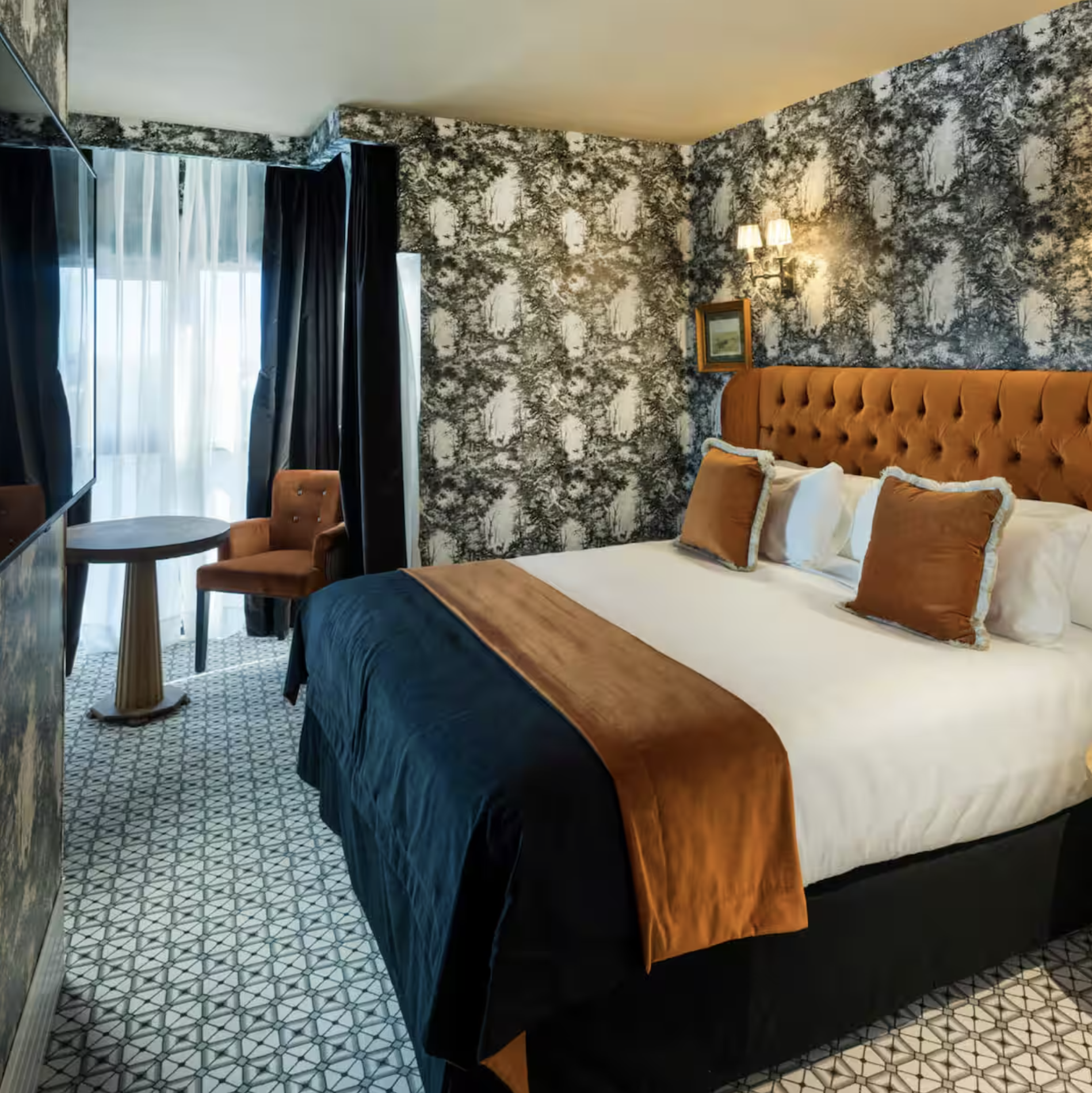 Casa Verbena Madrid guest room with patterned wallpaper and an upholstered bed