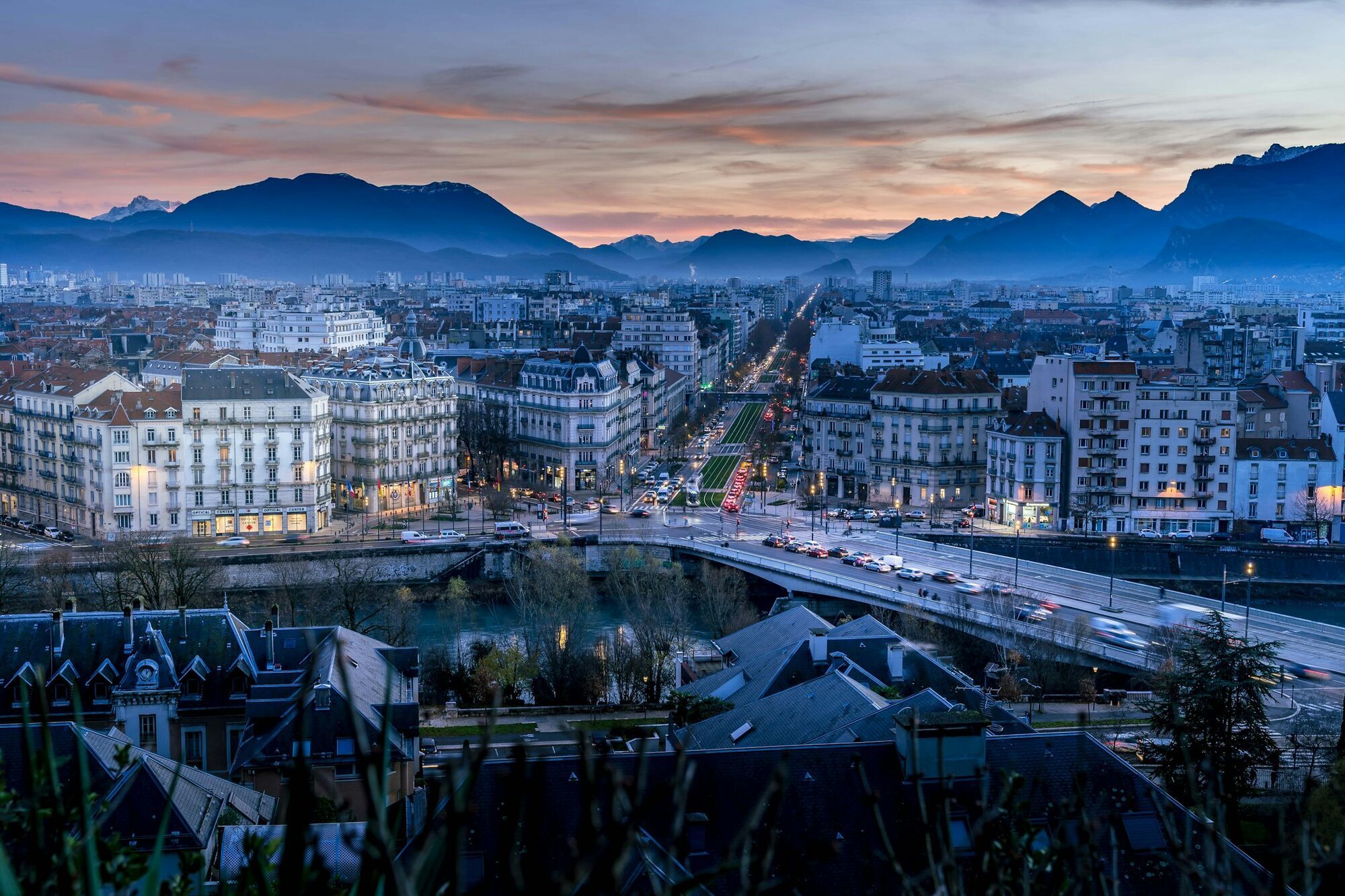 Panoramic view of Grenoble at dusk with the French Alps in the background