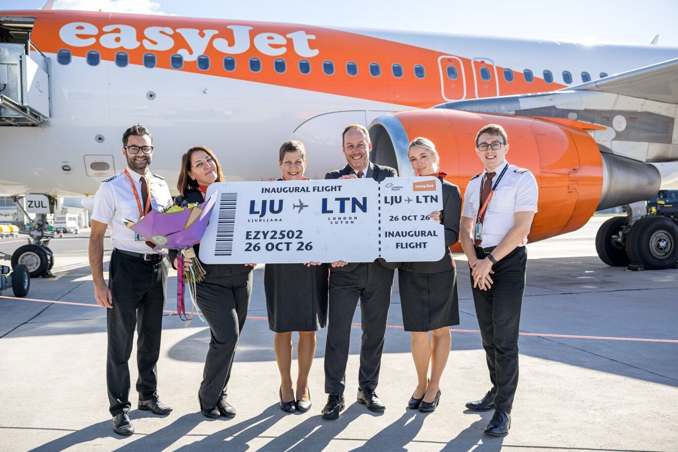 easyJet crew and airport representatives celebrating the first Ljubljana–Luton flight beside an aircraft
