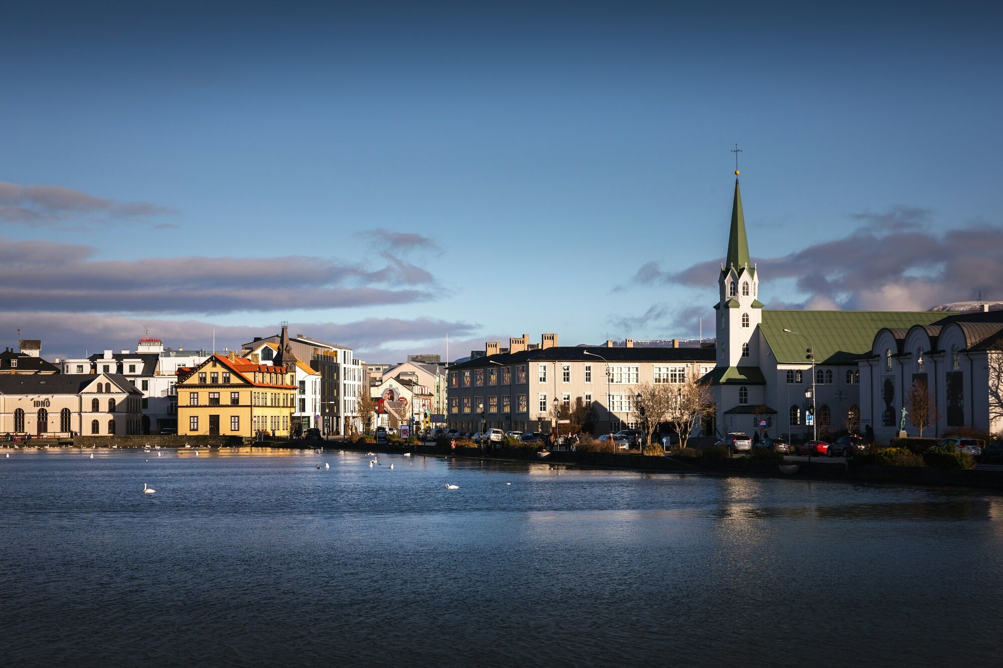 Lakeside buildings and a green-spired church in Reykjavik