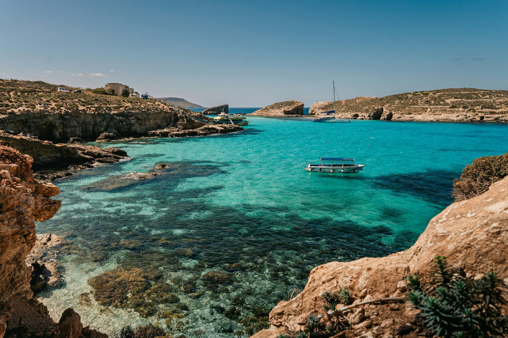 Turquoise waters and boats in a rocky bay in Malta
