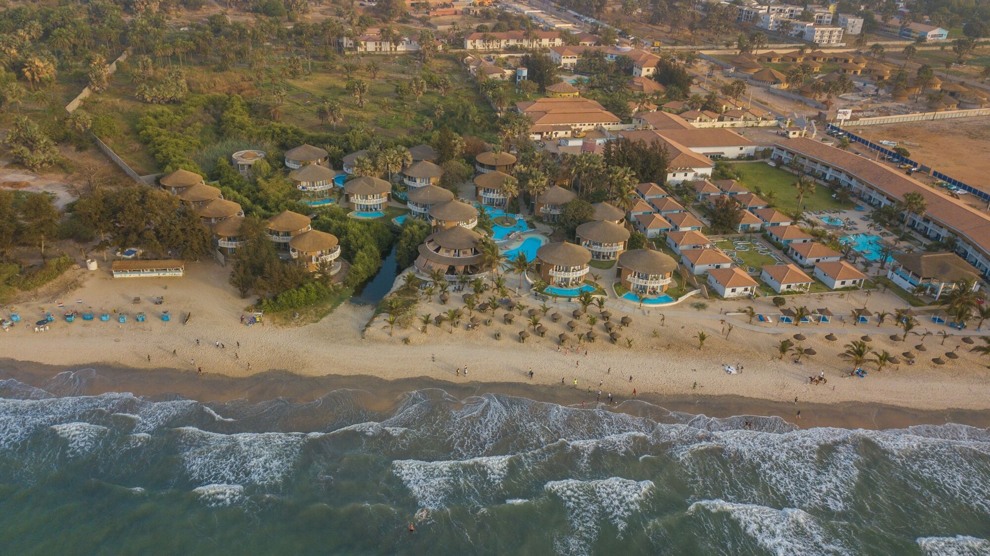 Aerial view of a beachfront resort with swimming pools and villas on The Gambia's Atlantic coast