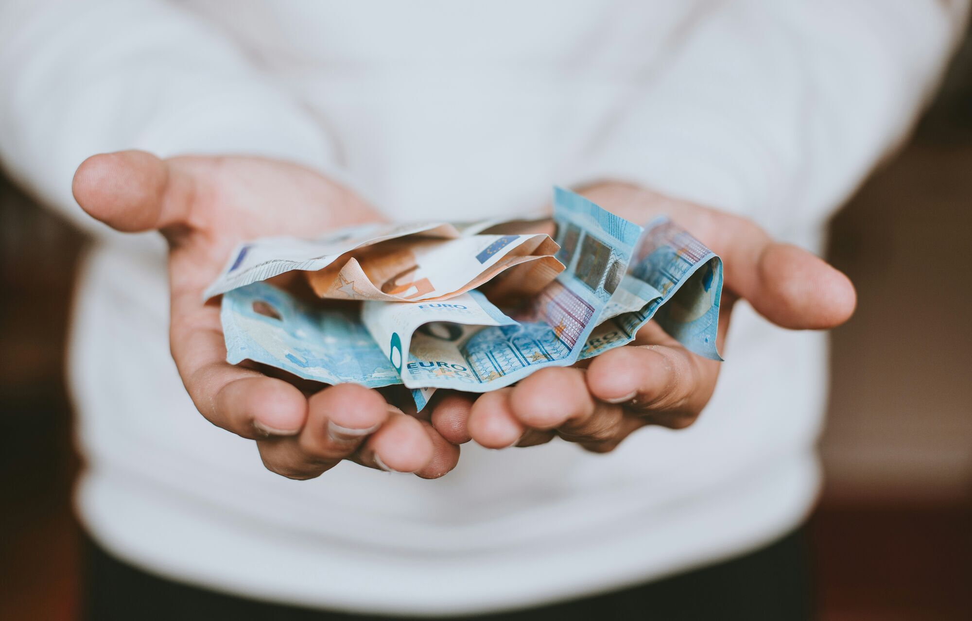 Person holding crumpled euro banknotes in both hands