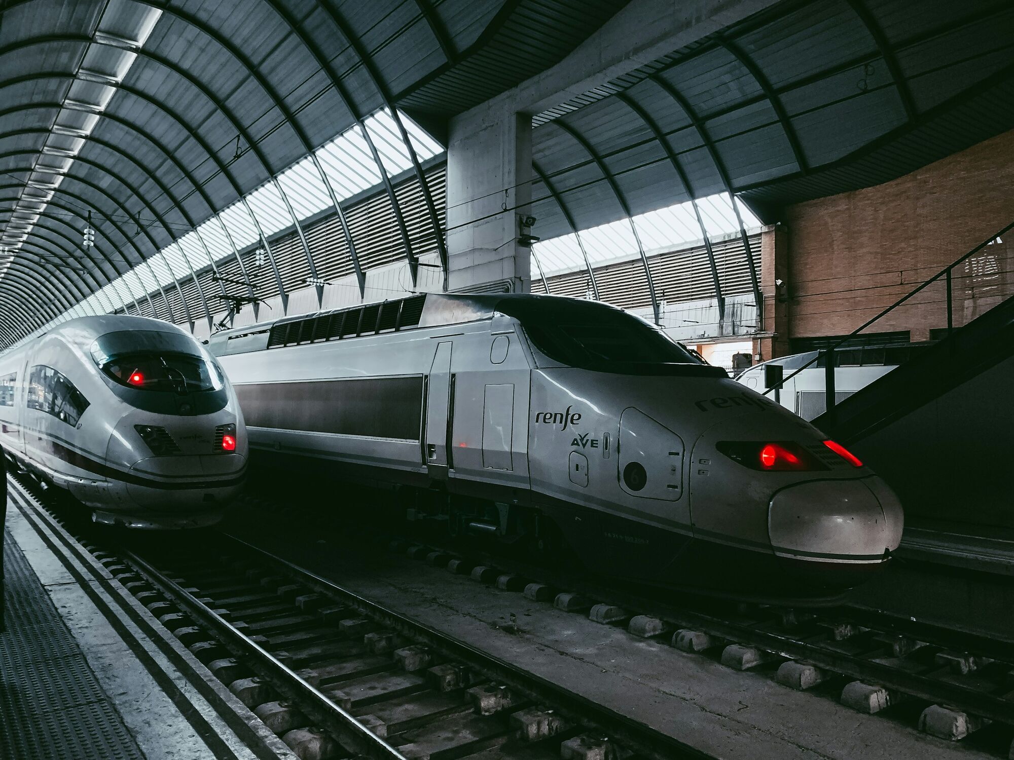 Two Renfe high-speed trains at a covered railway station