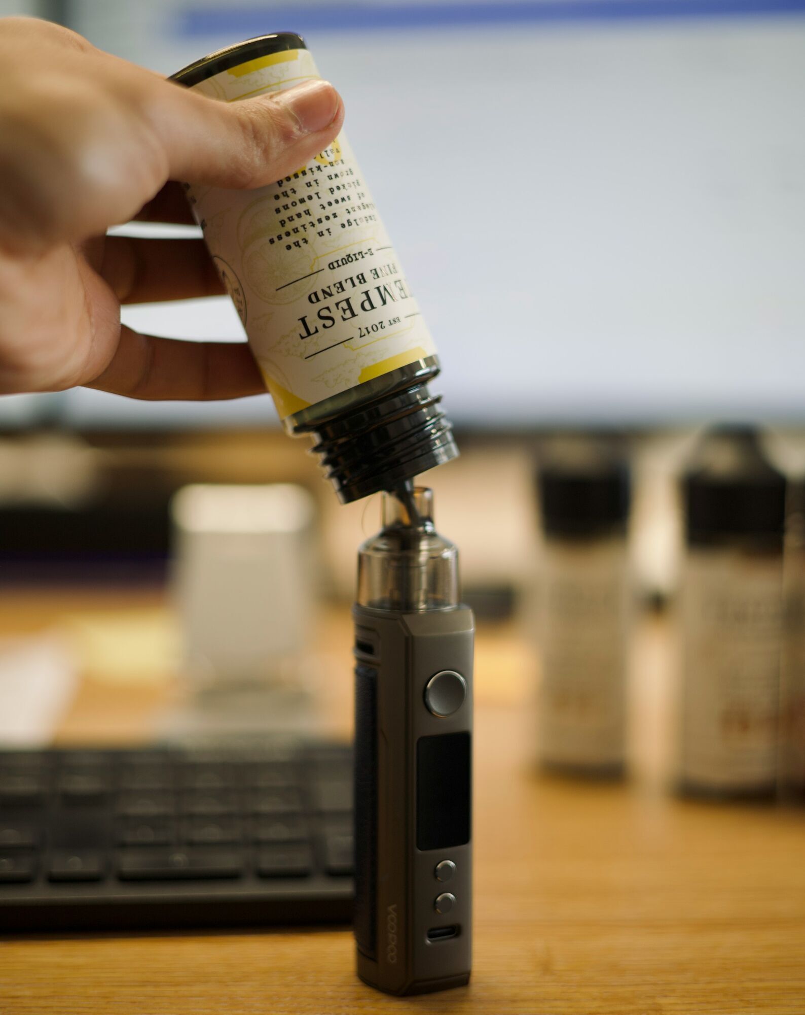 Vape device beside 100ml e-liquid bottle