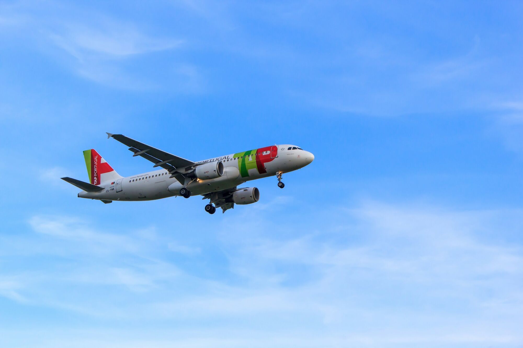 TAP Air Portugal aircraft flying against a blue sky