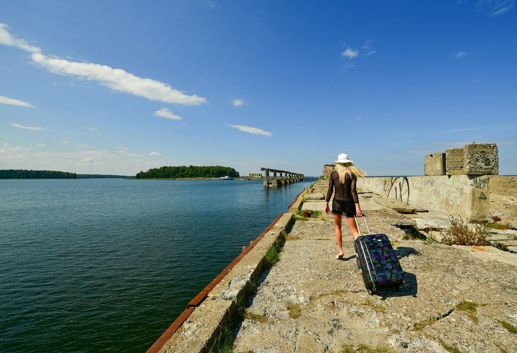 Woman pulling a suitcase along a waterfront pier