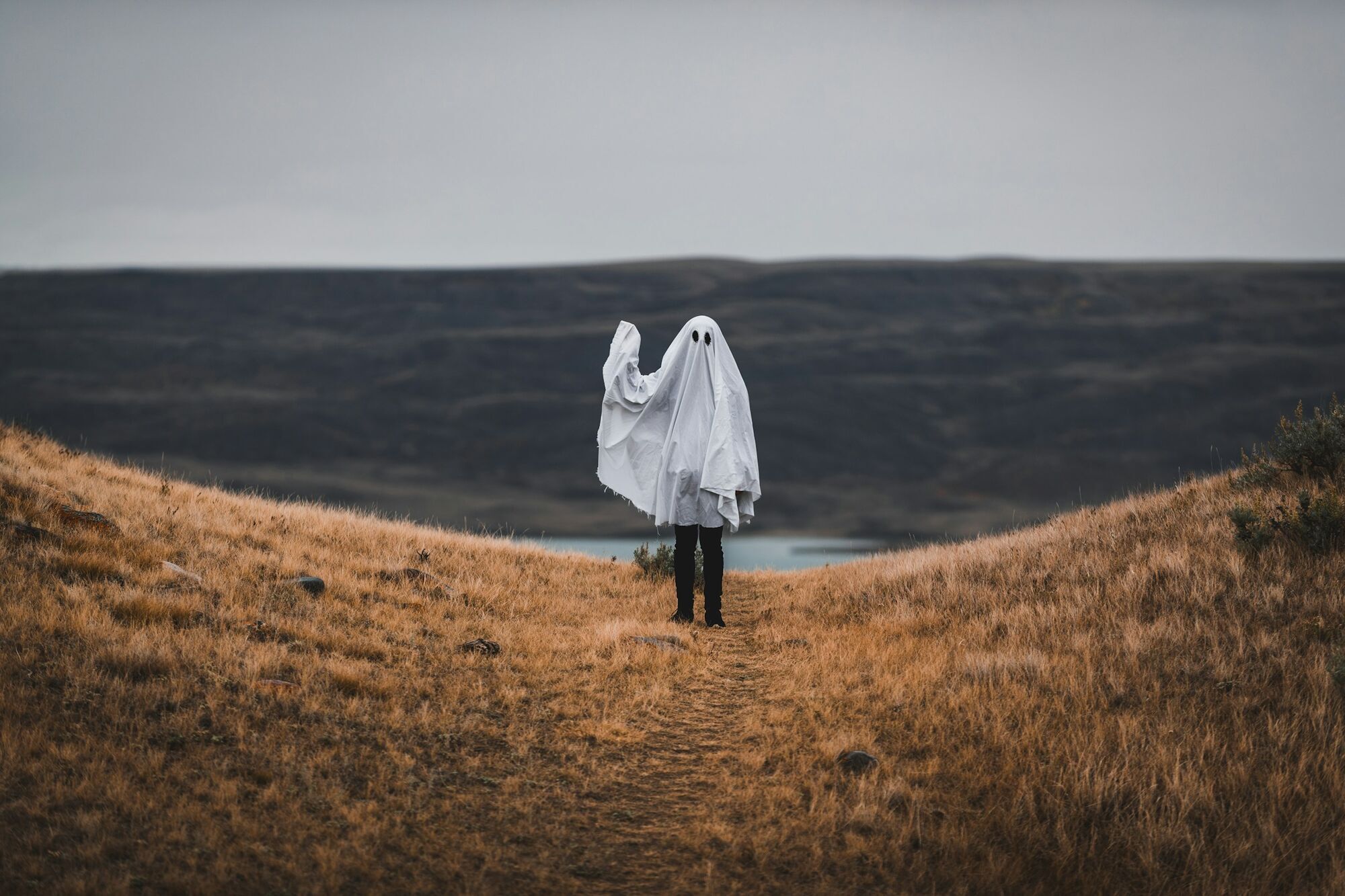 Person dressed as a ghost standing on a deserted hillside