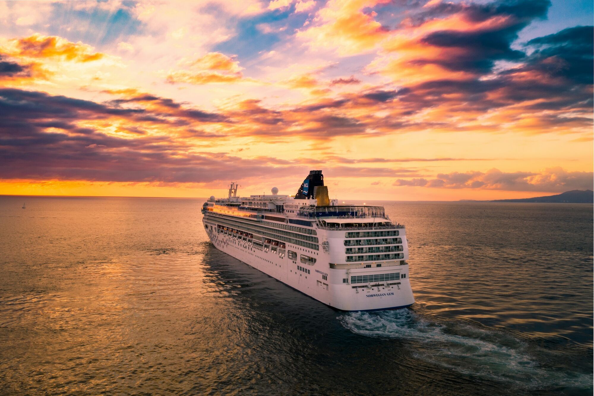 Norwegian Gem cruise ship sailing at sunset