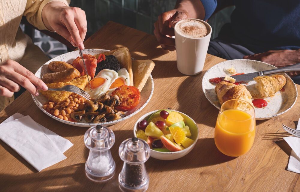 Two guests enjoying a cooked breakfast with eggs, sausages, beans and pastries