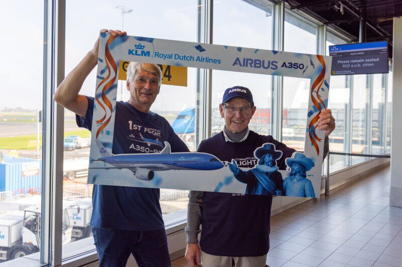 Two men holding a commemorative KLM Airbus A350 first-flight frame
