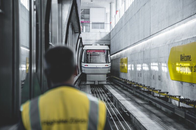Airport worker watching a Skymetro train in a tunnel