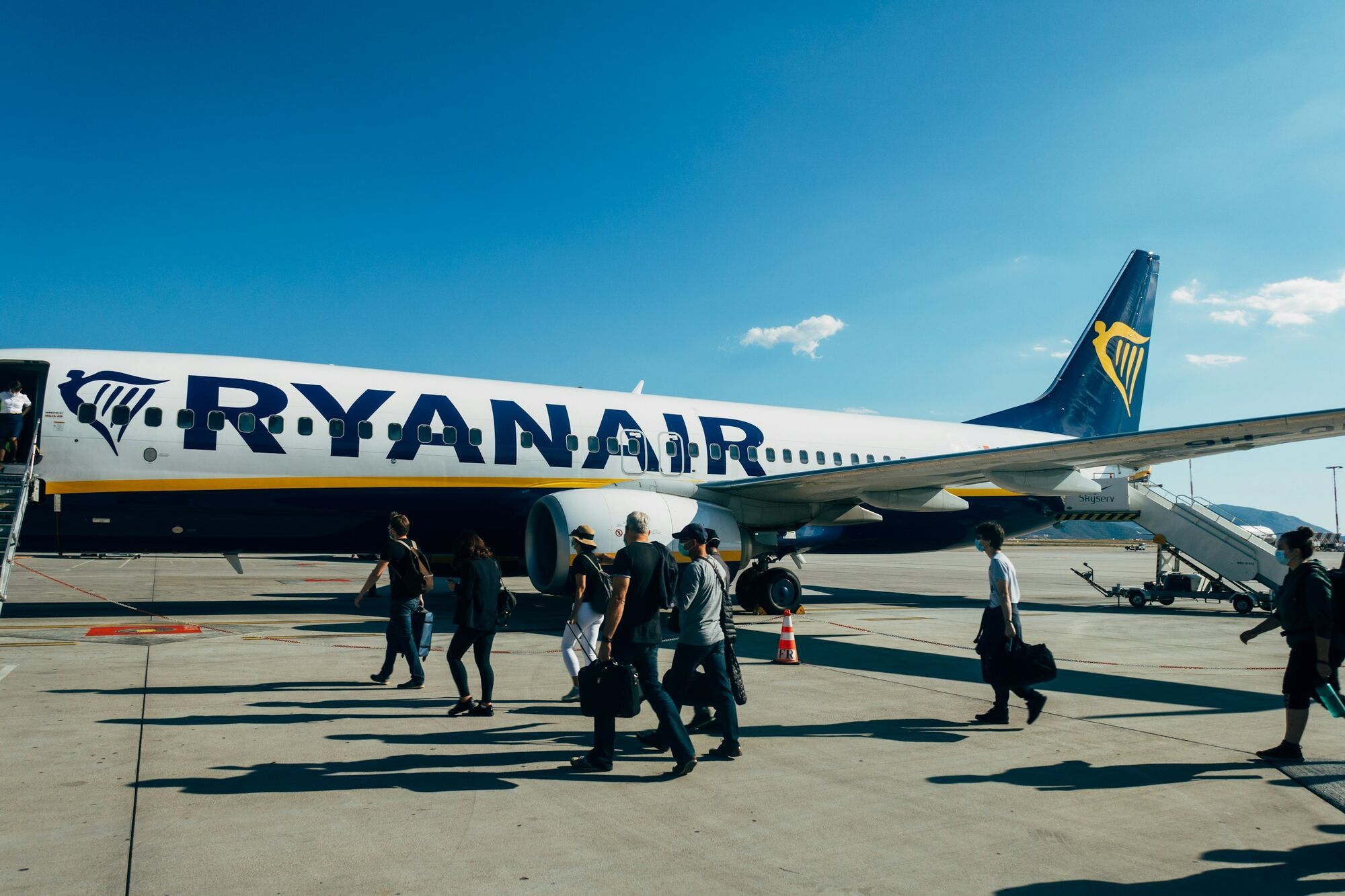 Passengers walking across an airport apron towards a Ryanair aircraft