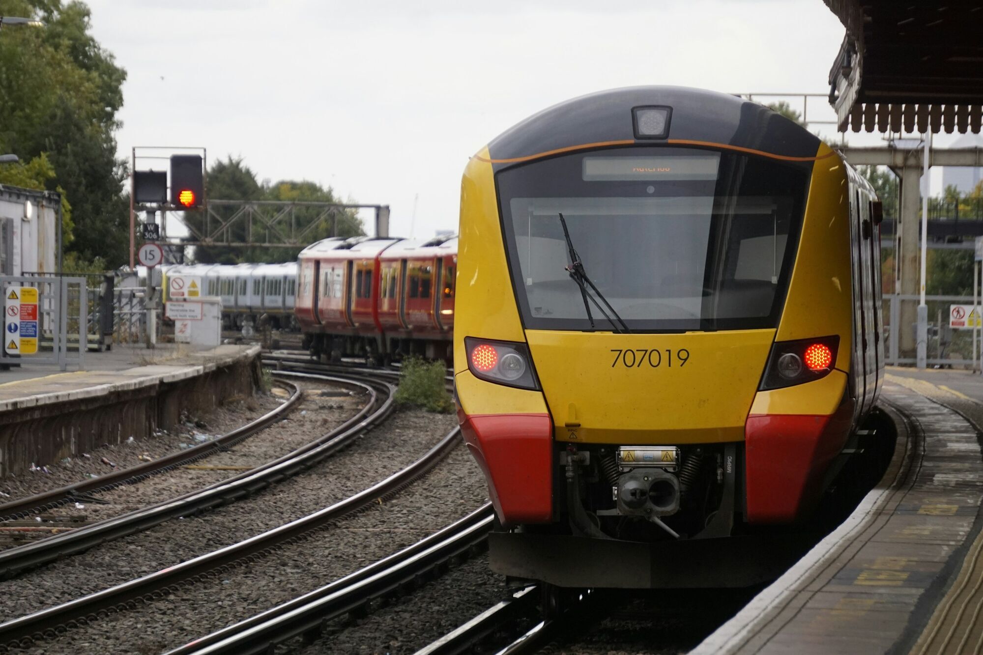 Yellow-fronted Class 707 train standing at a railway platform