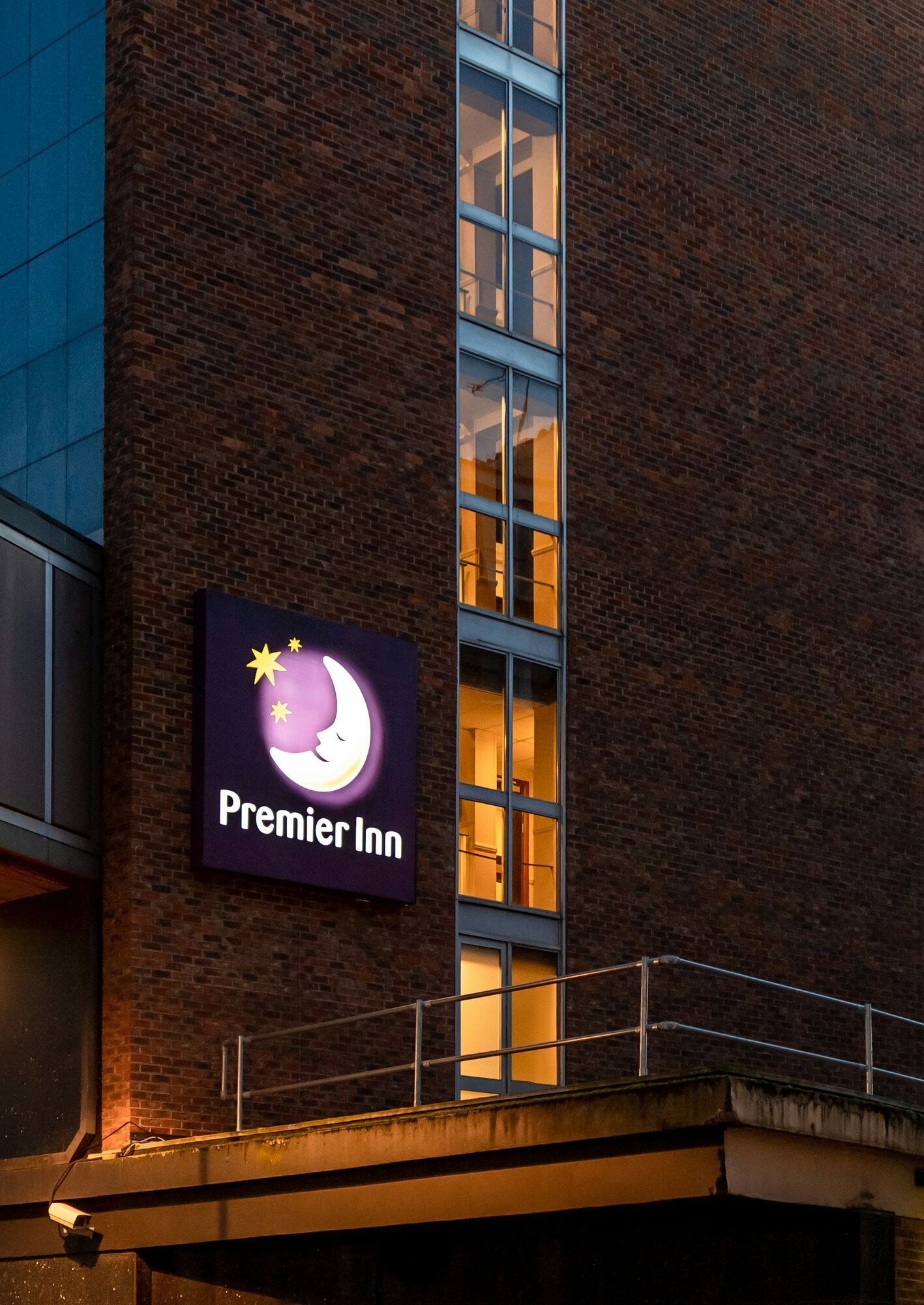 Illuminated Premier Inn sign on a brick hotel exterior at dusk