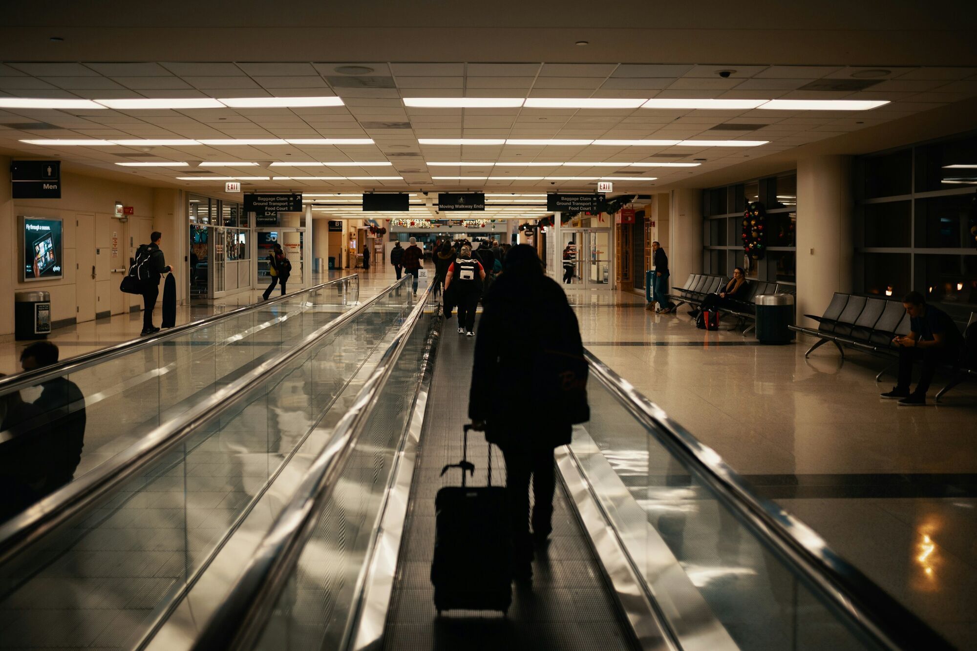 Passenger walking through airport terminal with luggage during travel disruption