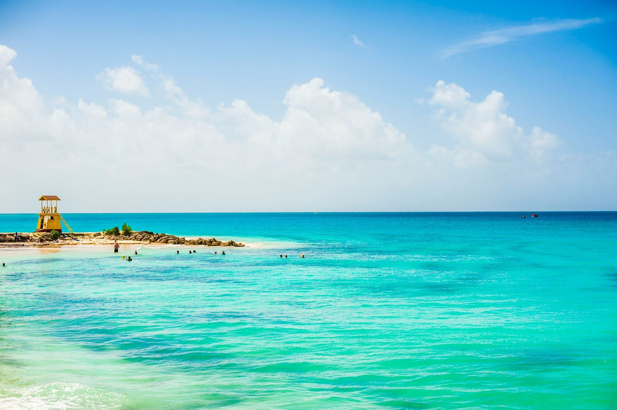 Turquoise waters and sandy beach in Barbados with swimmers and lifeguard tower
