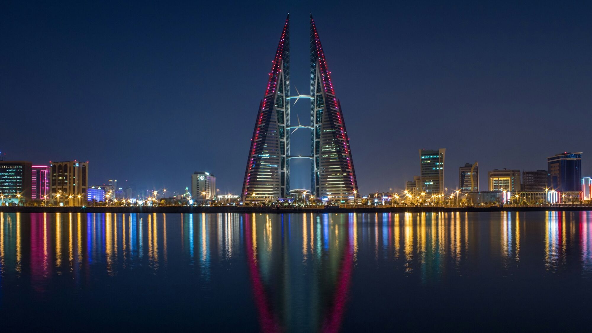 Bahrain World Trade Center illuminated at night with city lights reflected on the water