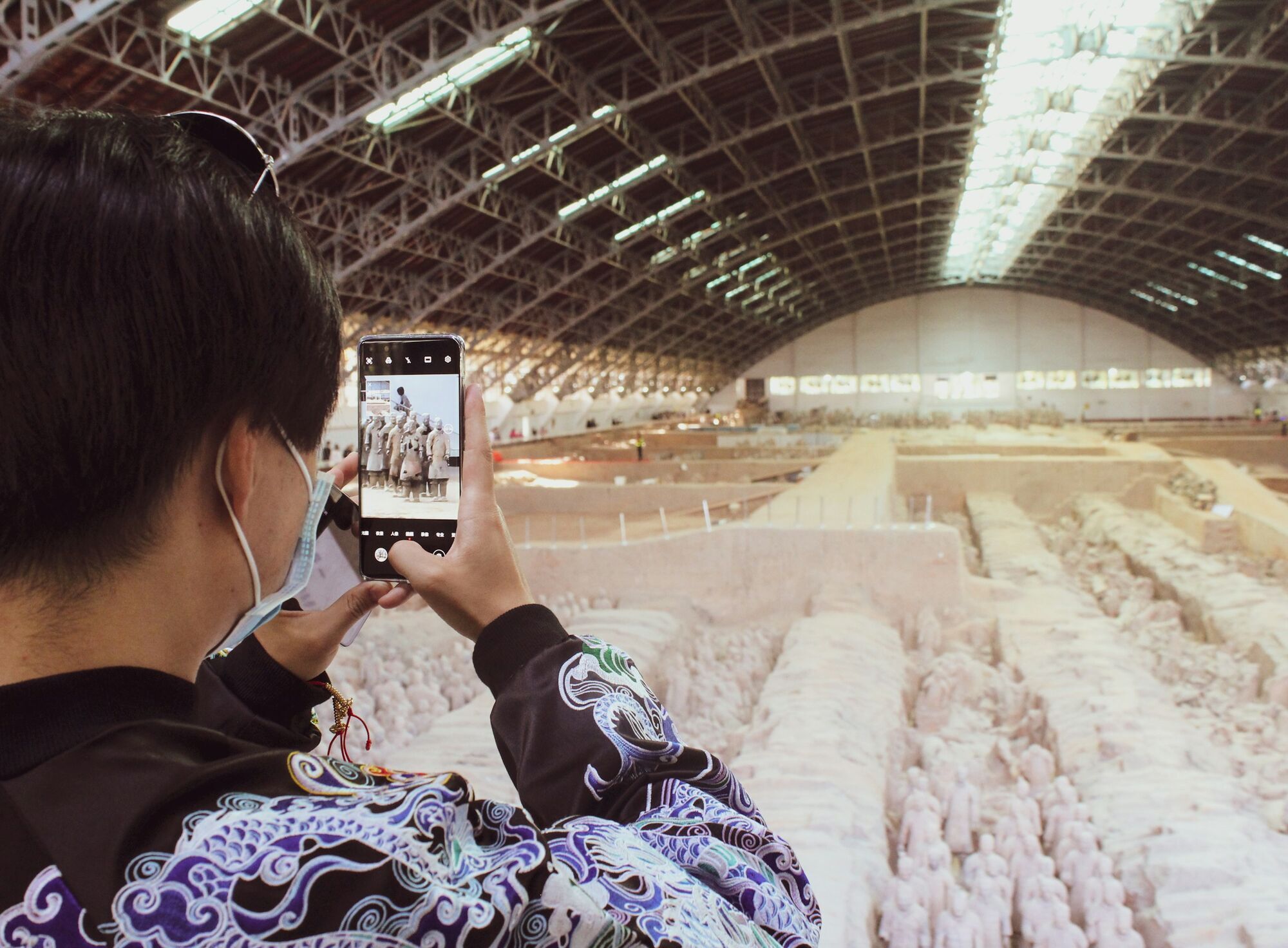 Visitor photographing the Terracotta Army inside exhibition hall
