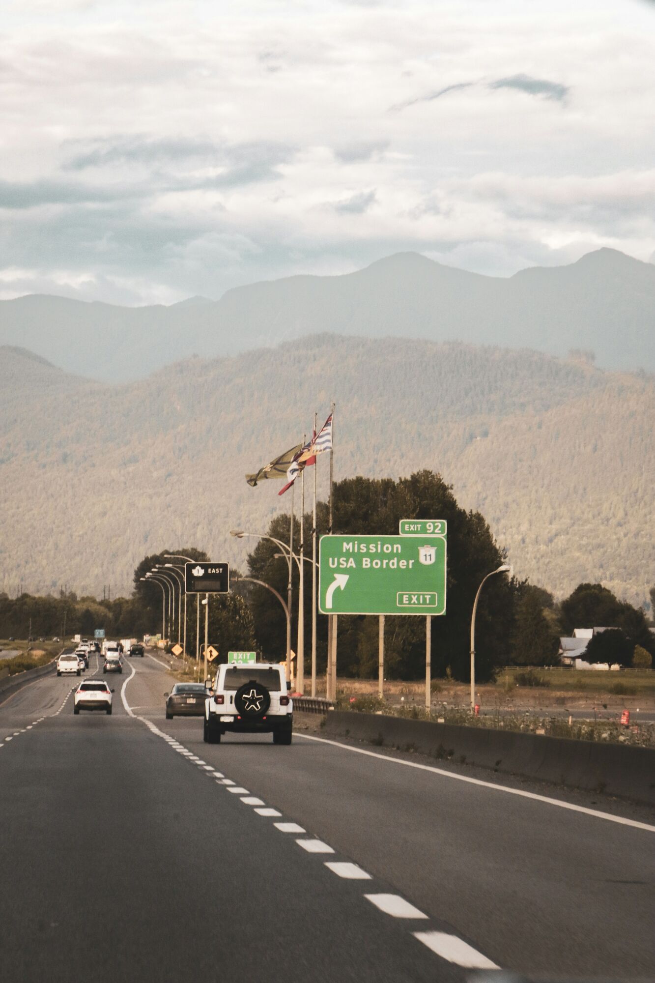 Highway sign pointing to USA border with mountains in the background