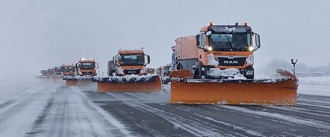 Airport snowplough vehicles clearing runway during blizzard conditions