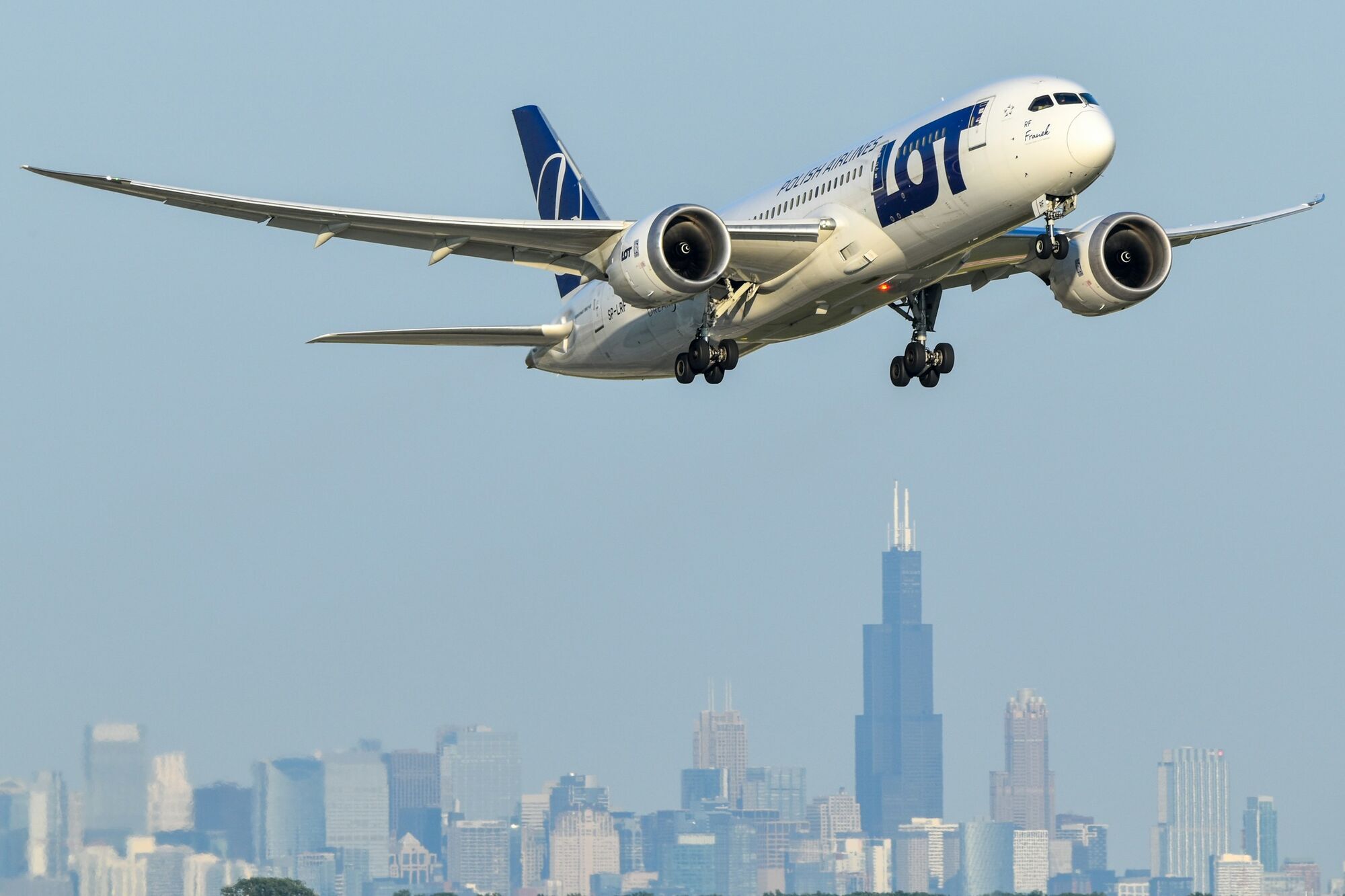LOT aircraft in flight above city skyline