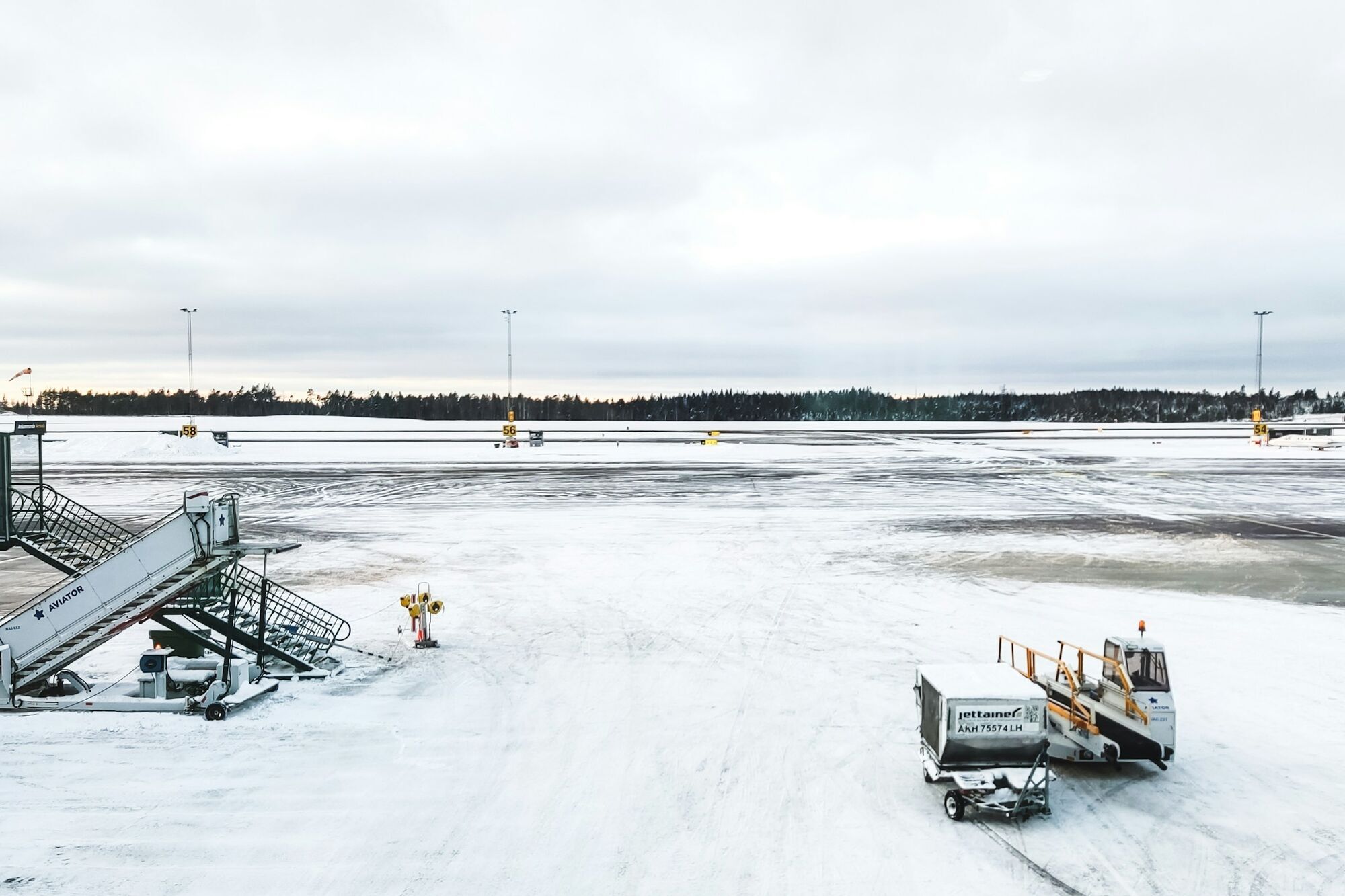 Snow-covered airport apron with ground equipment in winter conditions