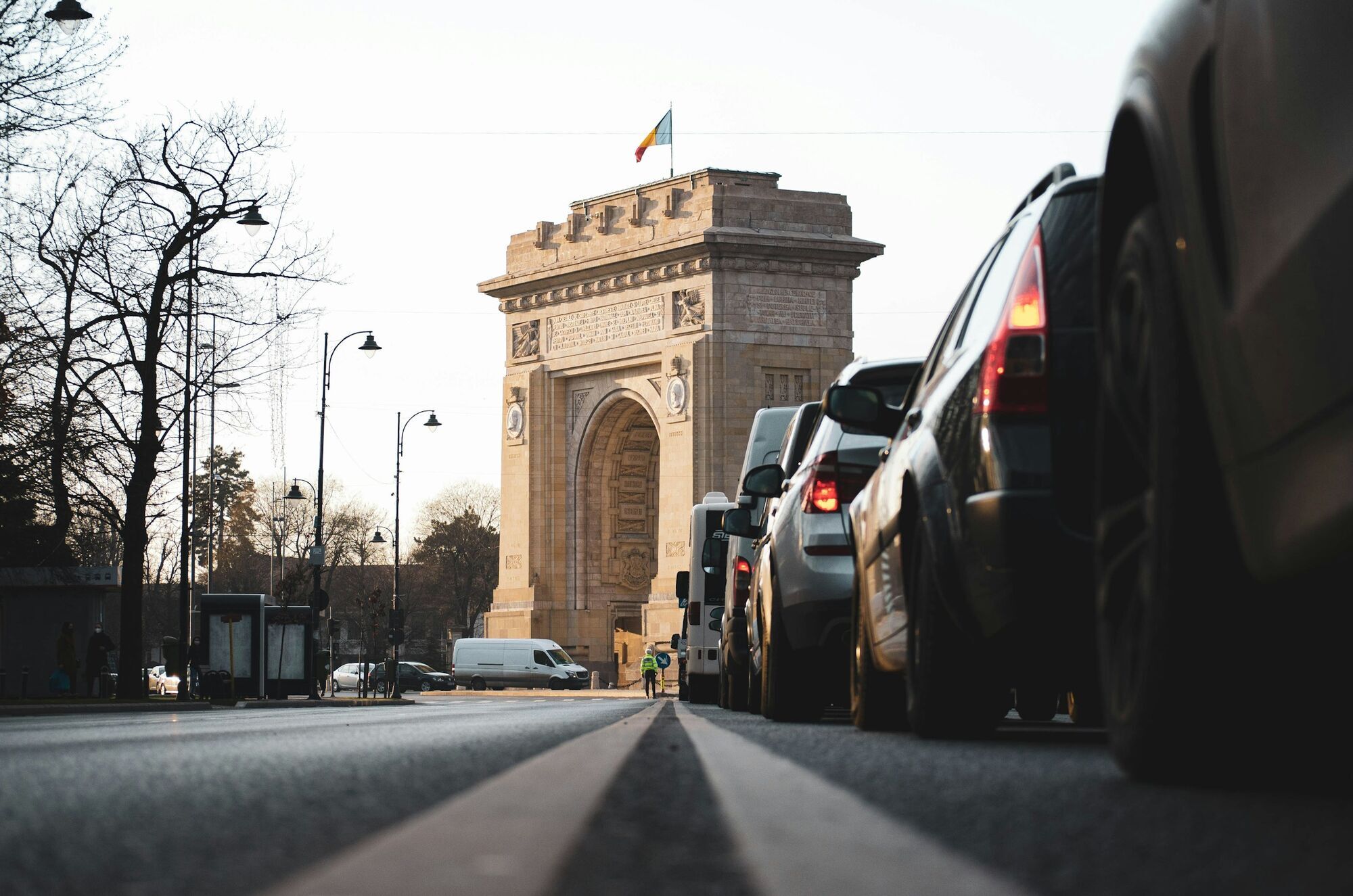 Cars driving past Bucharest’s Arch of Triumph in winter light