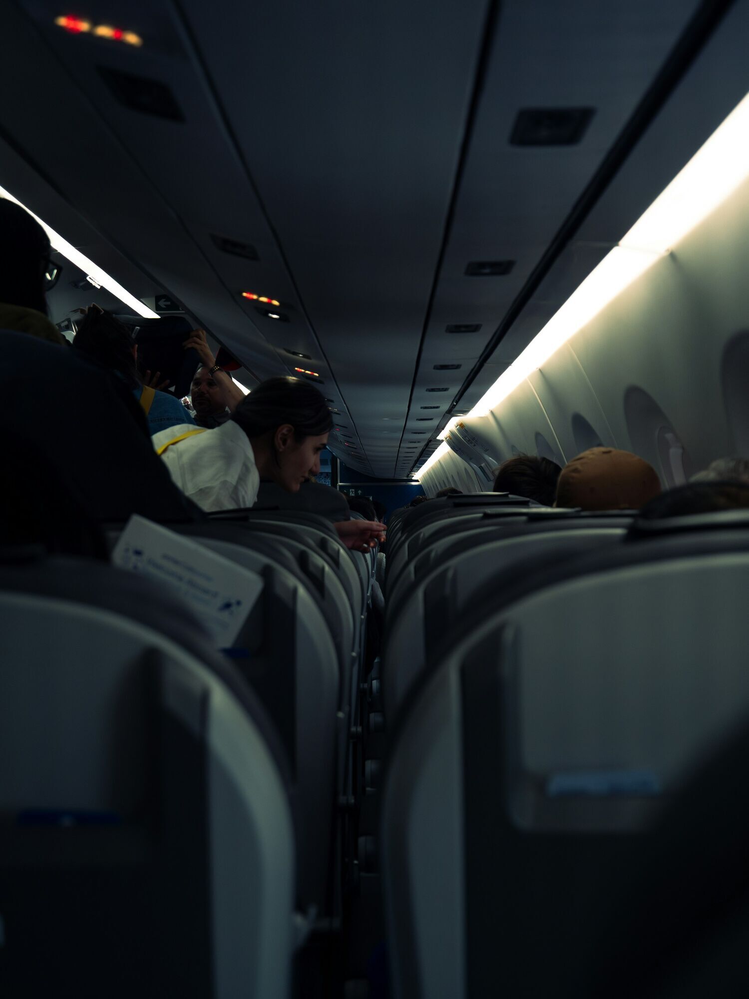 Passengers standing in a narrow aircraft aisle during boarding