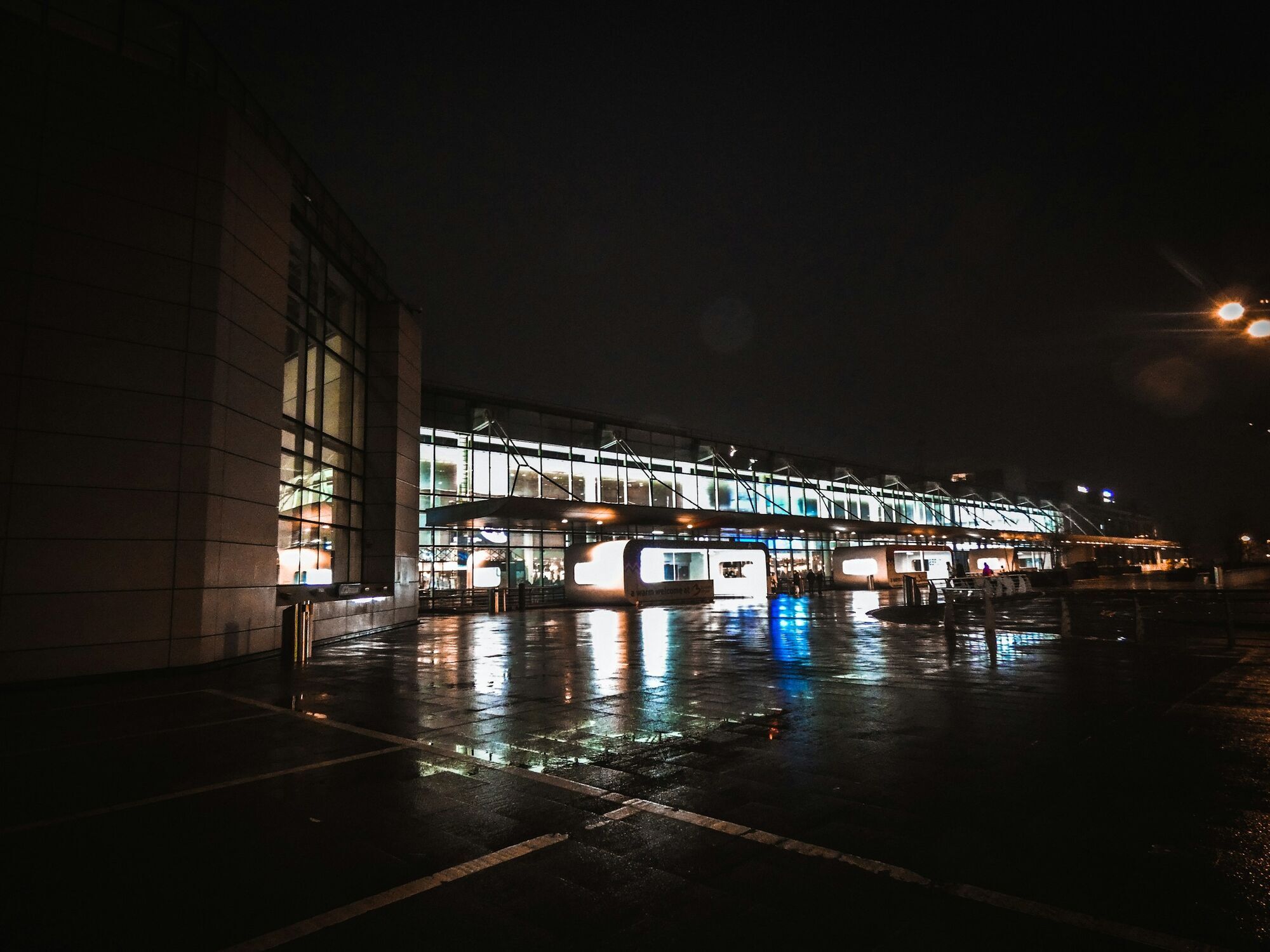 Brussels Airport terminal building illuminated at night with wet pavement