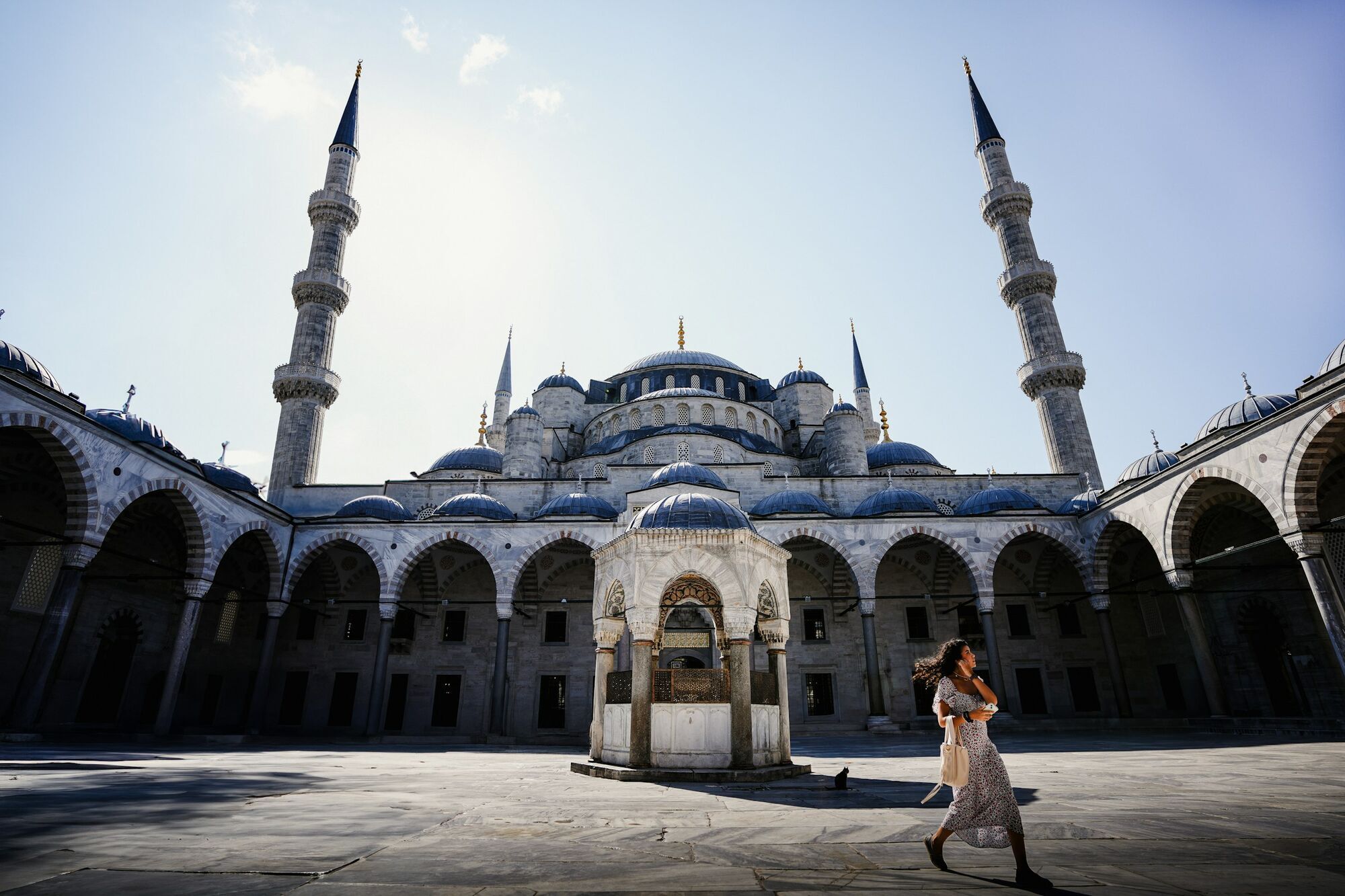 Courtyard of a historic Istanbul mosque with minarets and visitor walking