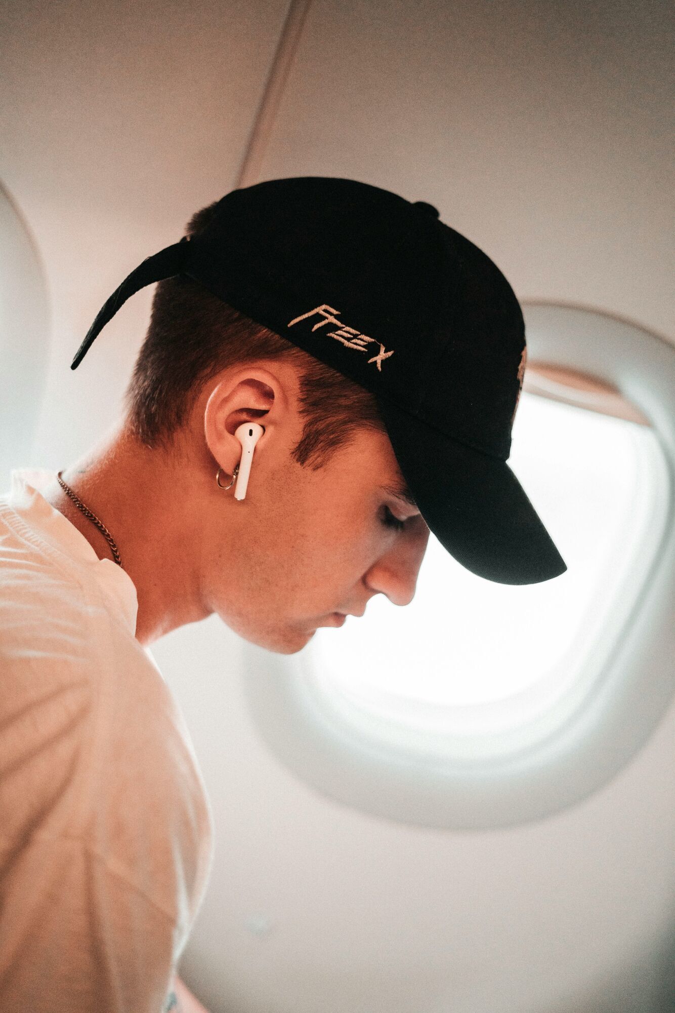 Passenger sitting on a plane wearing wireless earbuds
