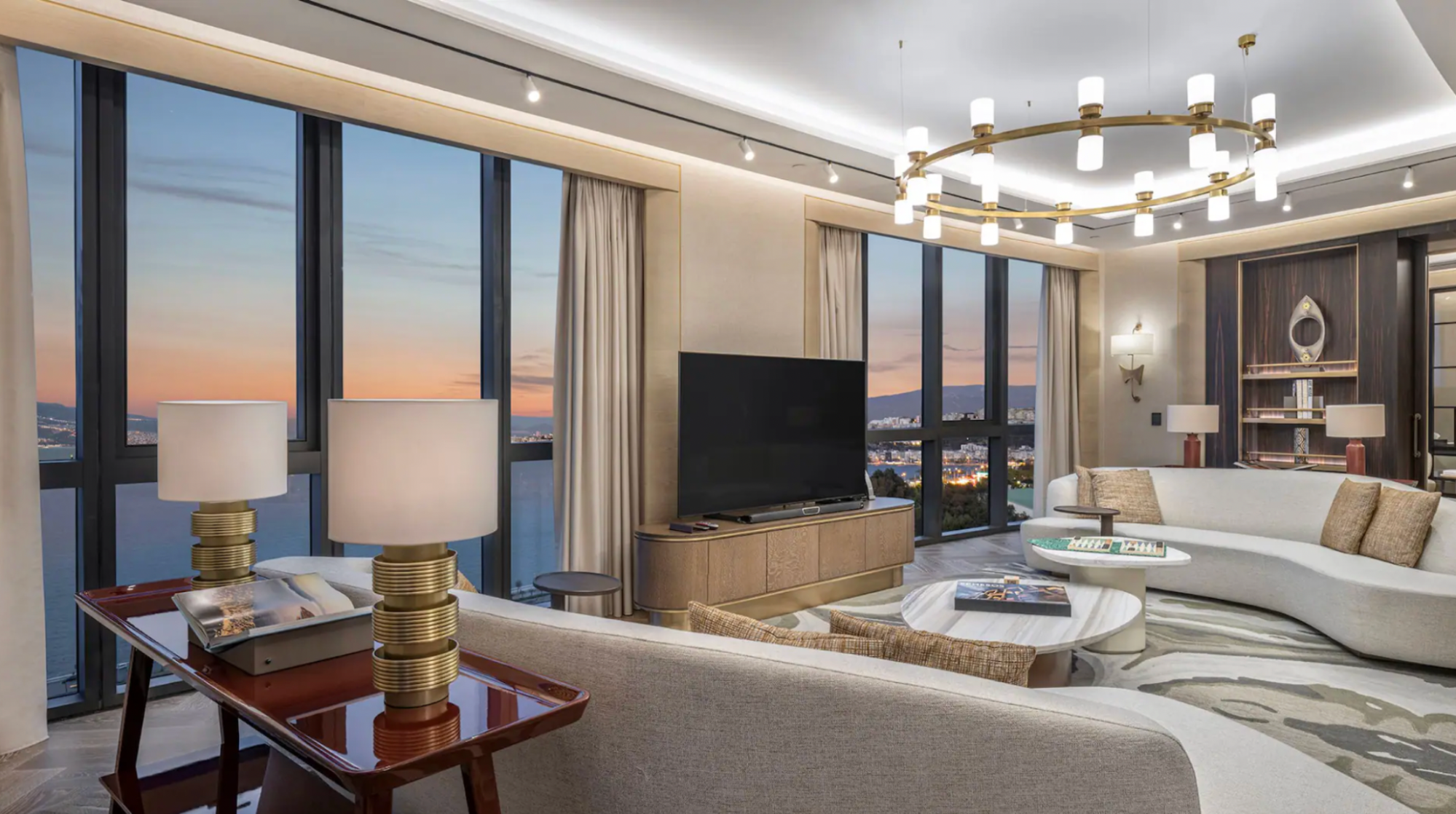 Spacious hotel suite with large windows overlooking city and sea