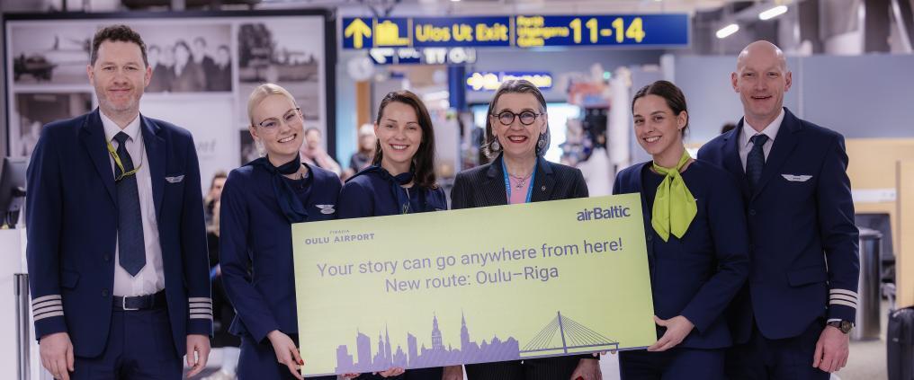 airBaltic team presenting new Oulu Riga route sign at airport
