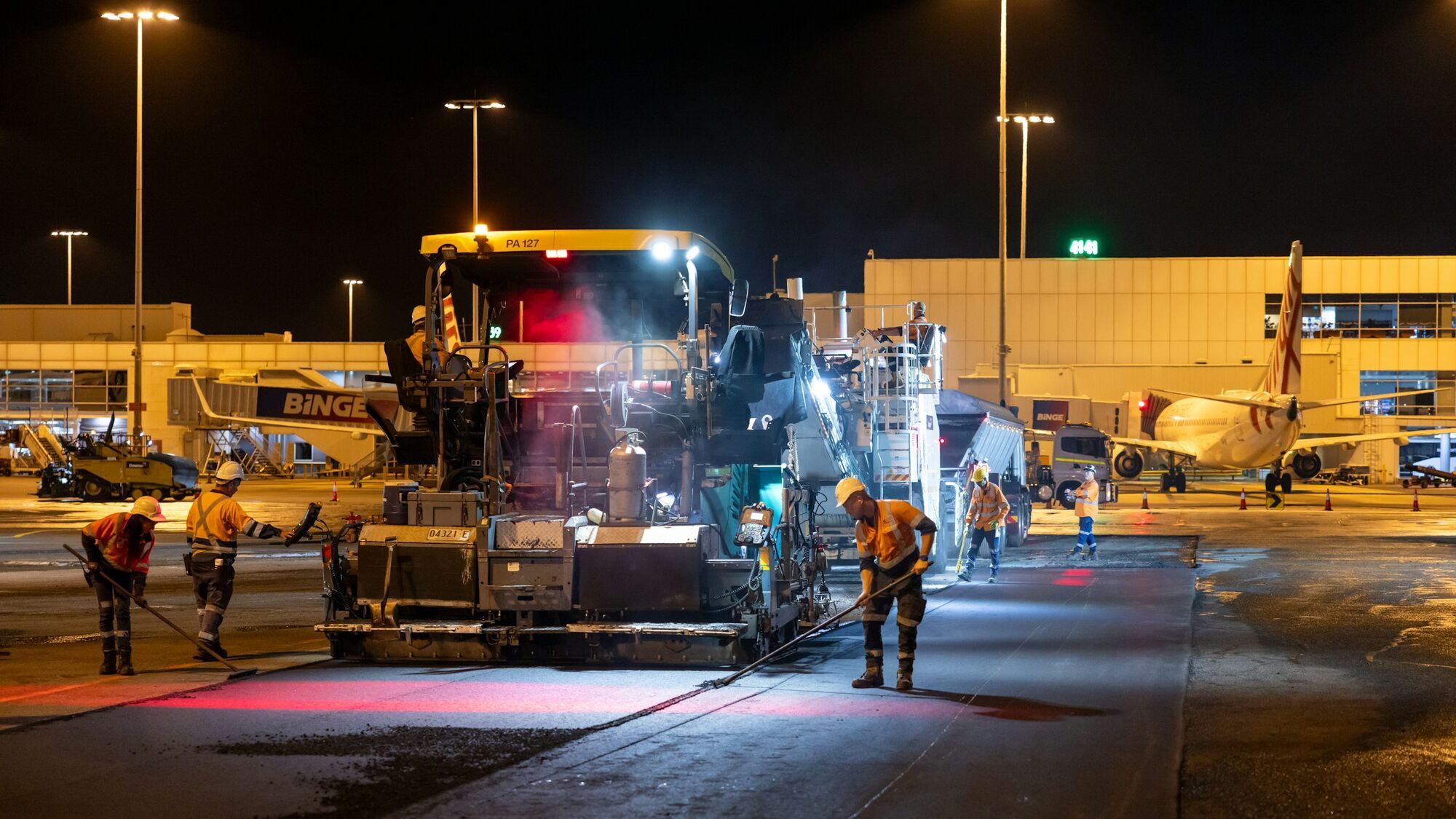 Construction machinery repairing airport runway at night