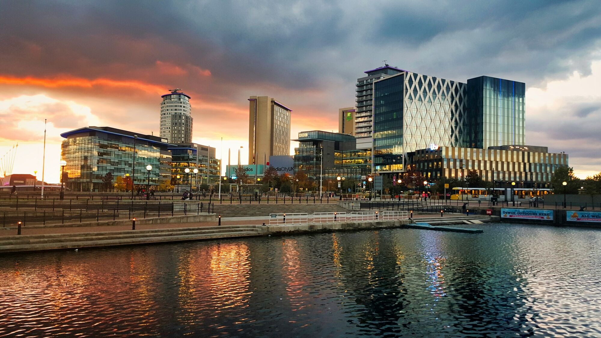 Manchester city skyline reflected in waterfront at sunset