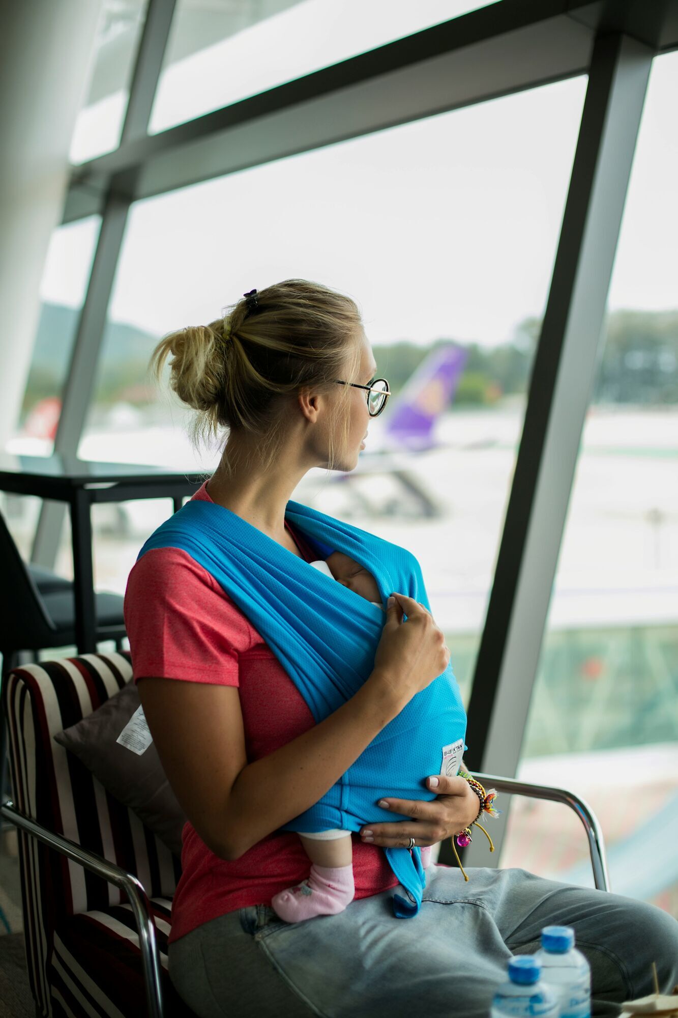 Mother with baby in sling waiting at airport terminal