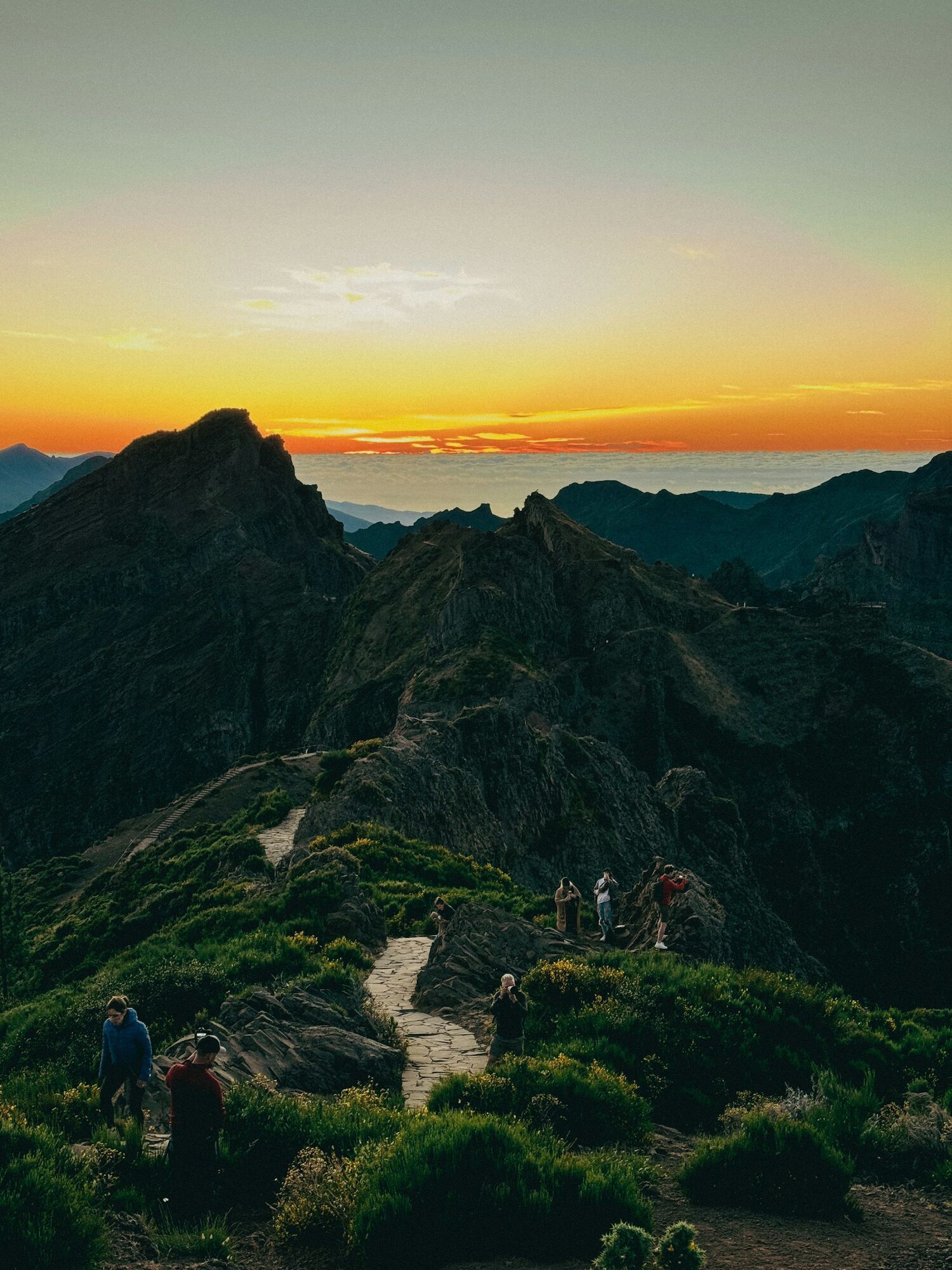 Hikers walking along narrow ridge at sunset in Madeira