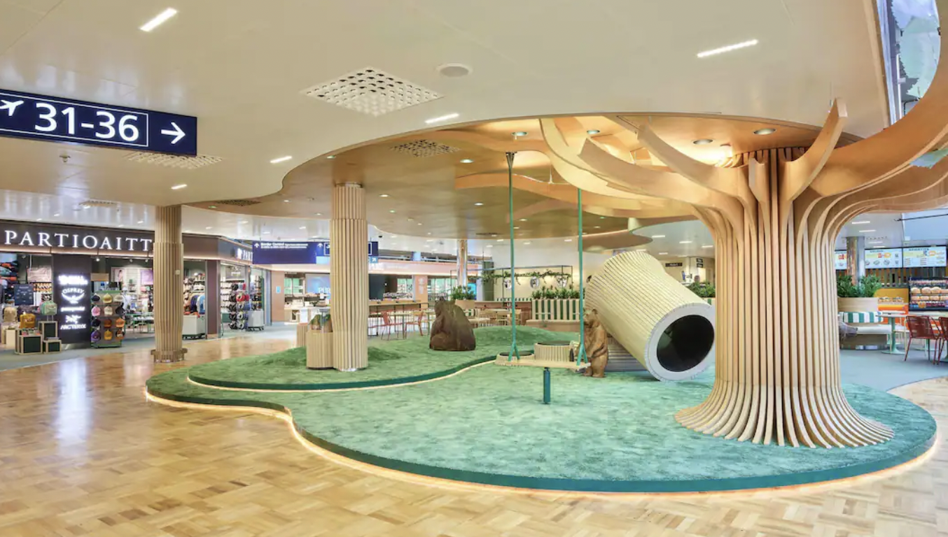 Schengen area near Gate 30 with wooden tree structure, seating and Nordic retail stores