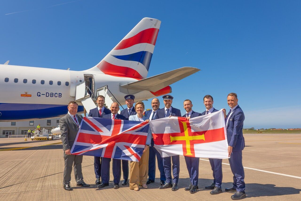 British Airways crew holding UK and Guernsey flags near aircraft