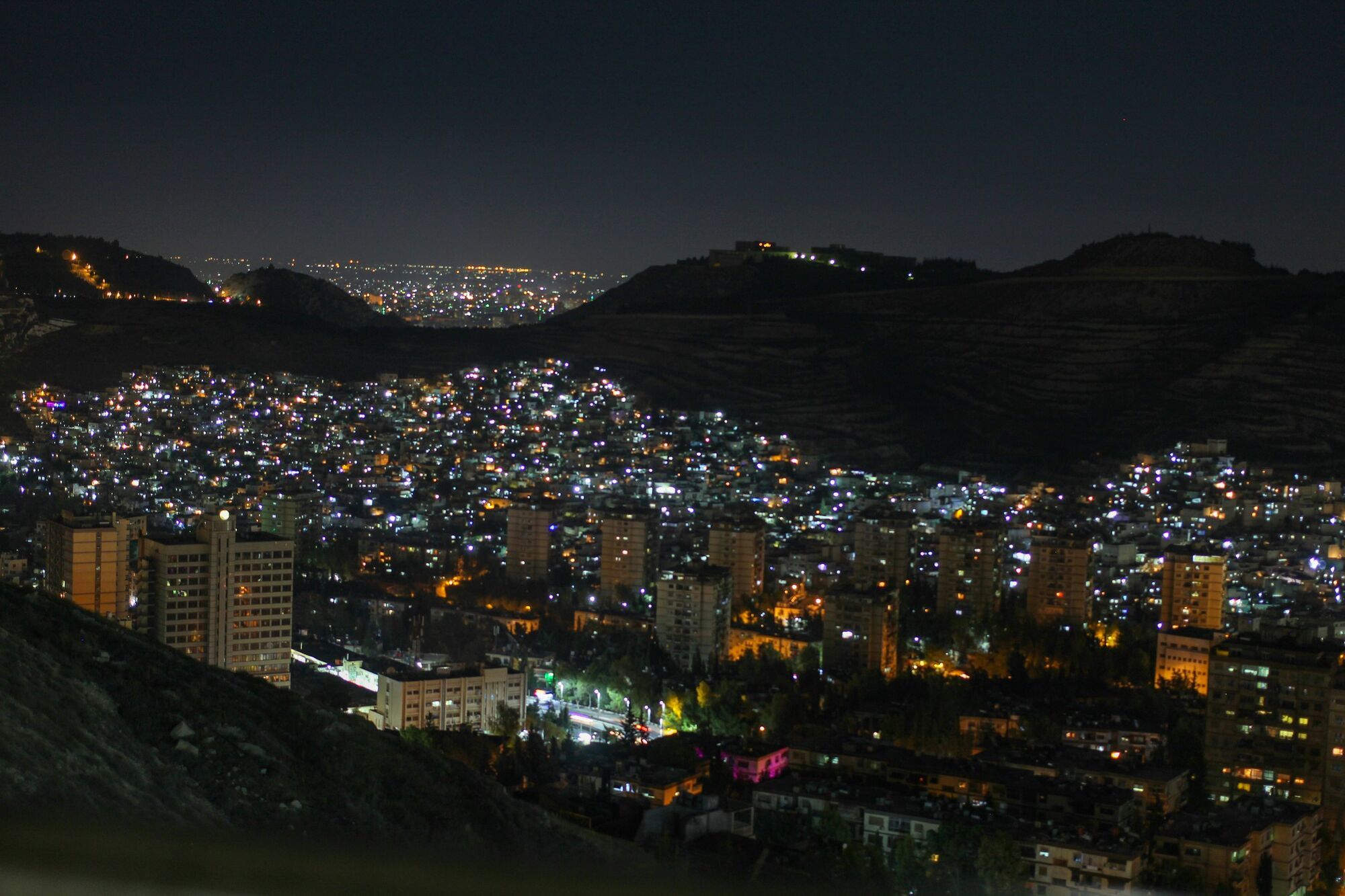 Night view of Damascus city with lights and hills