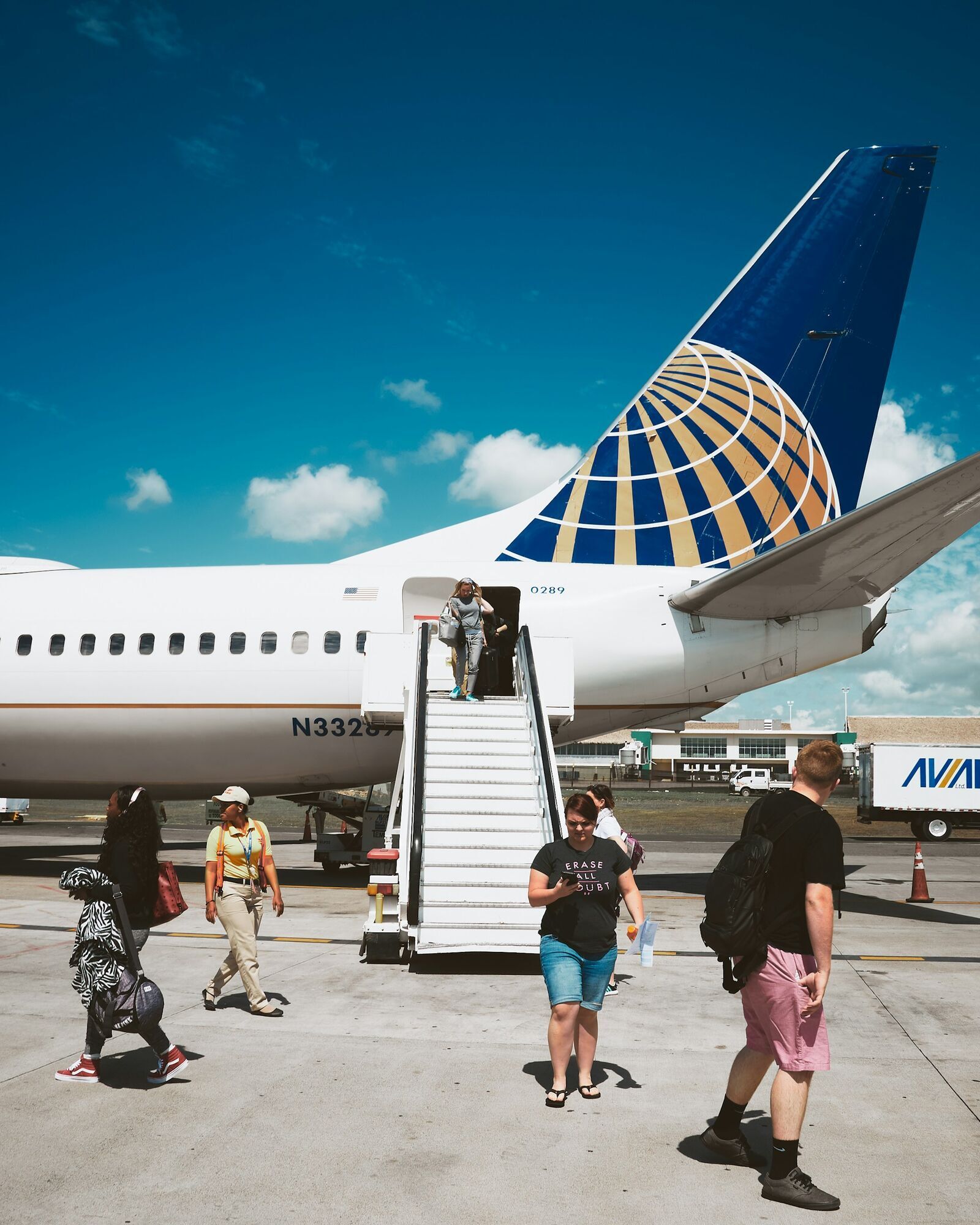 Passengers disembarking from an airplane on the tarmac at an airport