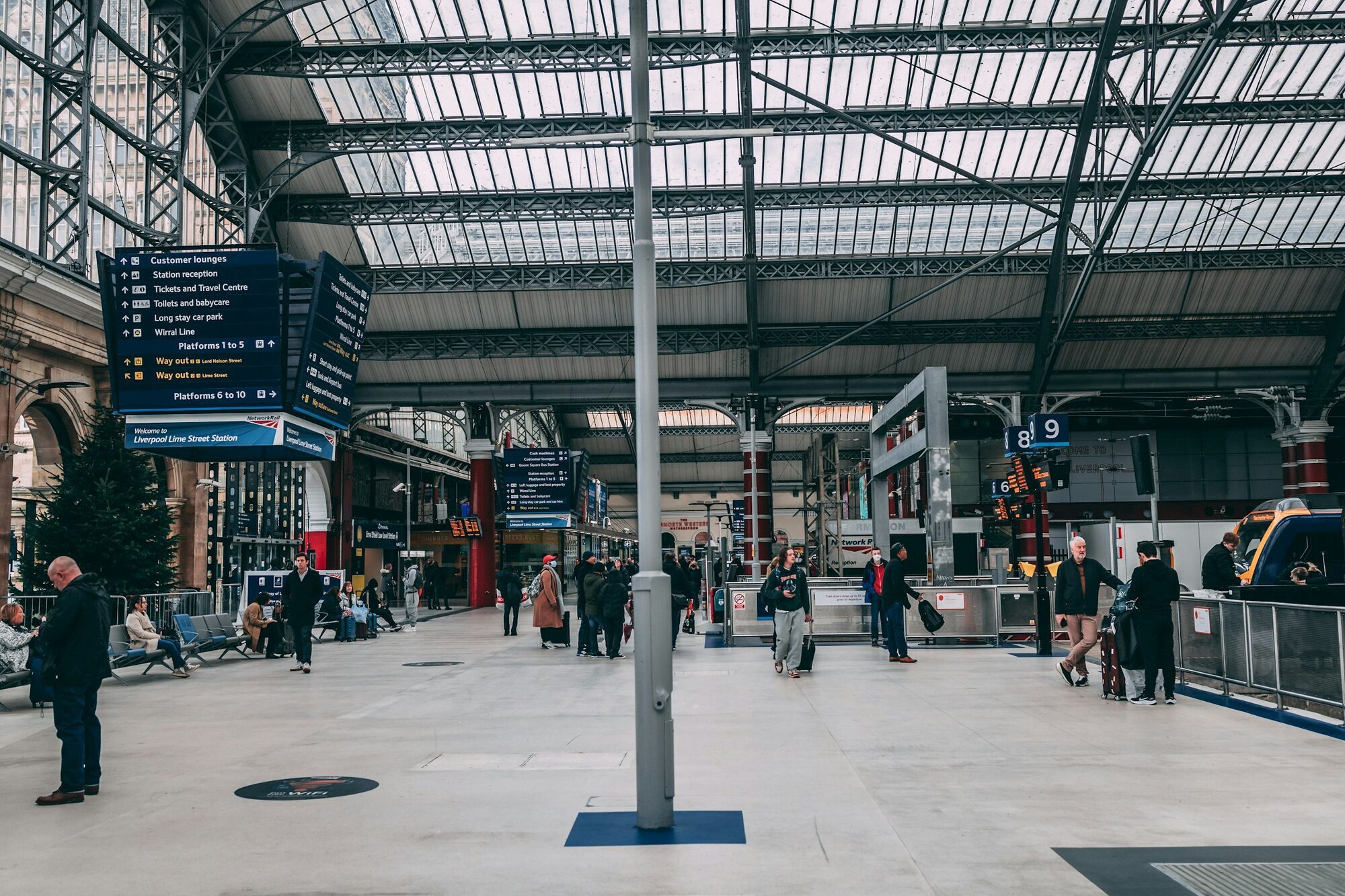 Passengers inside Liverpool Lime Street station concourse with platforms and signs