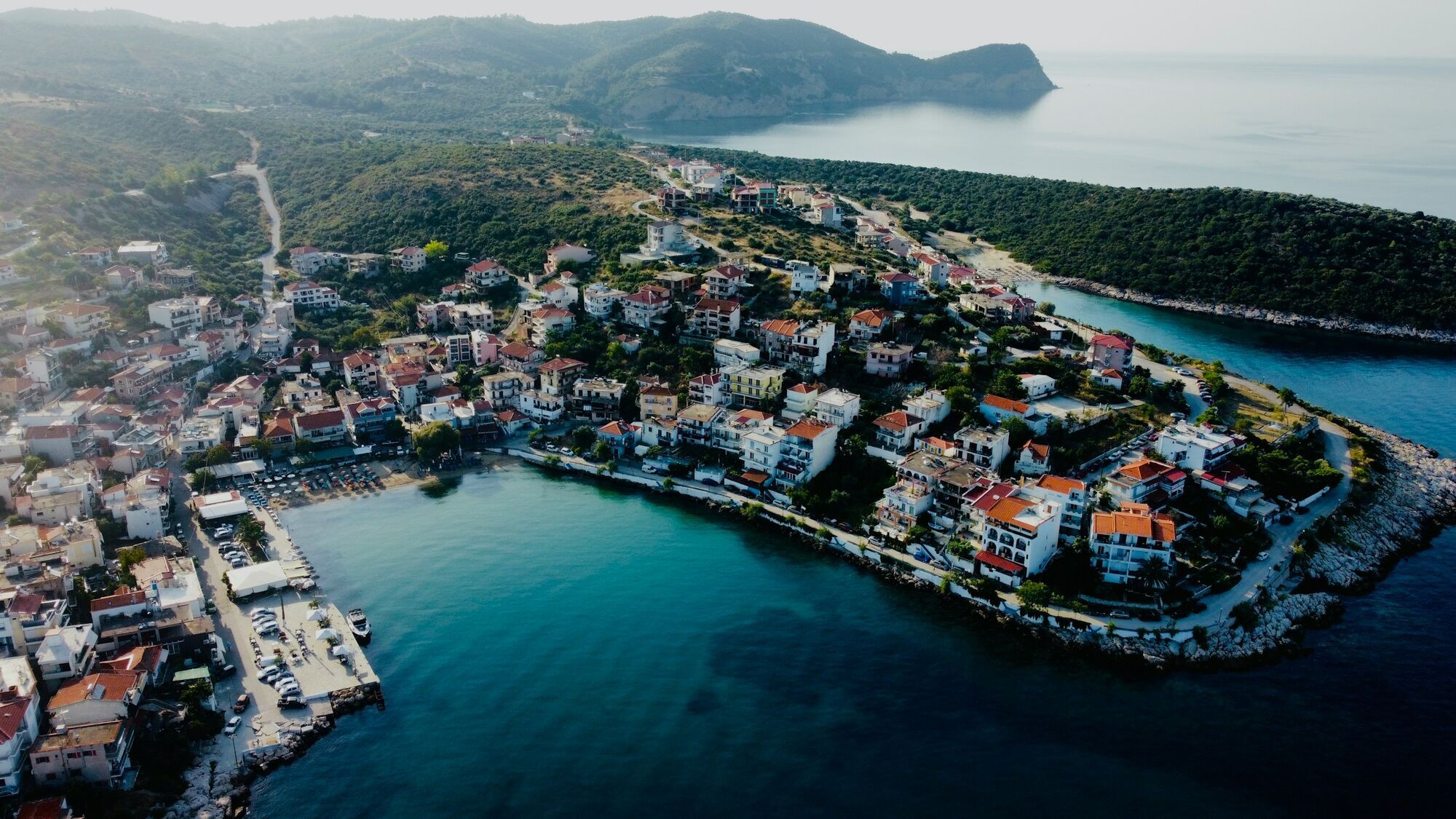 Aerial view of coastal town with harbour and hillside houses in northern Greece